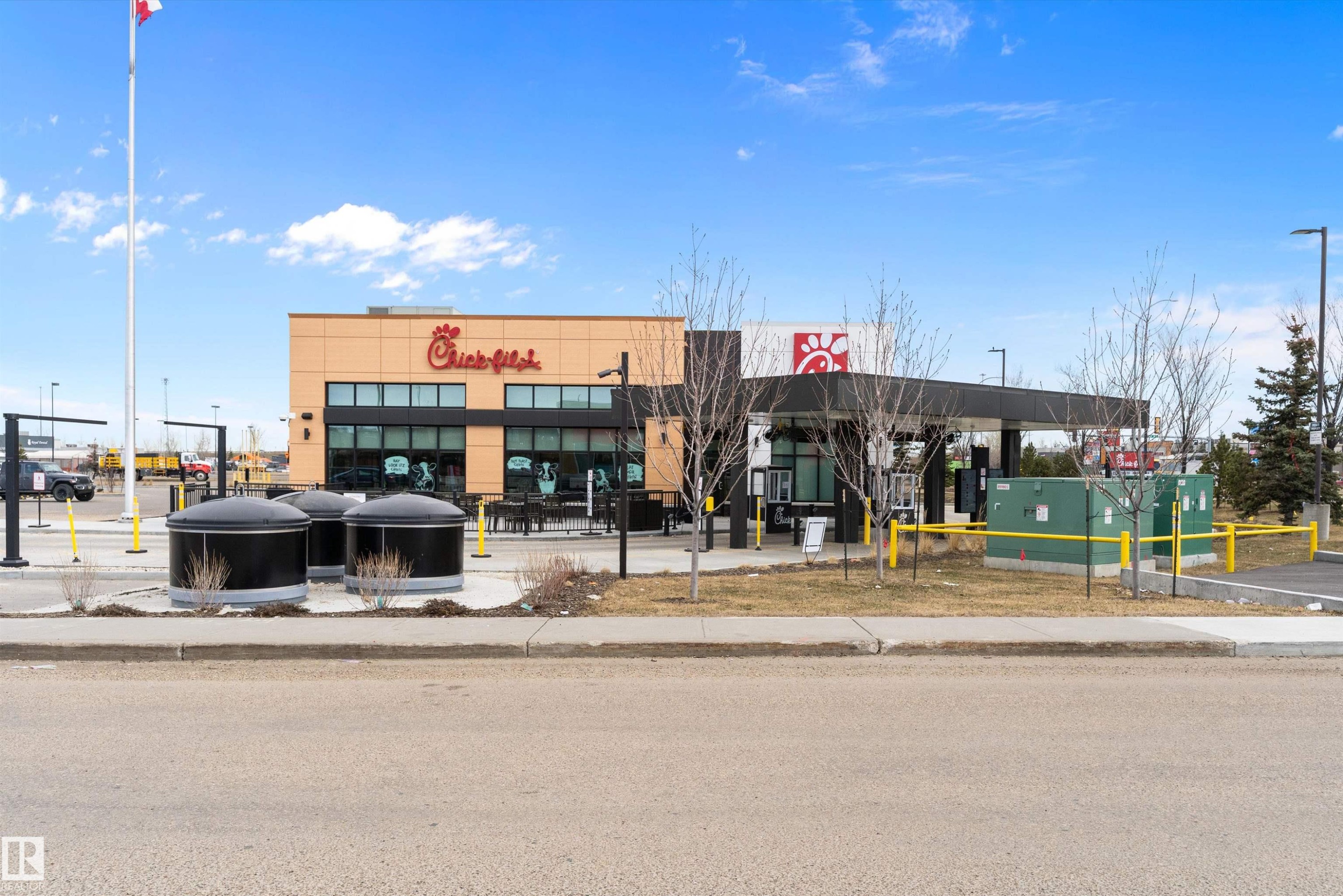 Contemporary commercial building featuring a light-colored facade with dark-framed windows, a drive-thru canopy, and exterior signage - 3314 9 Street Nw, Edmonton, AB - Outdoor