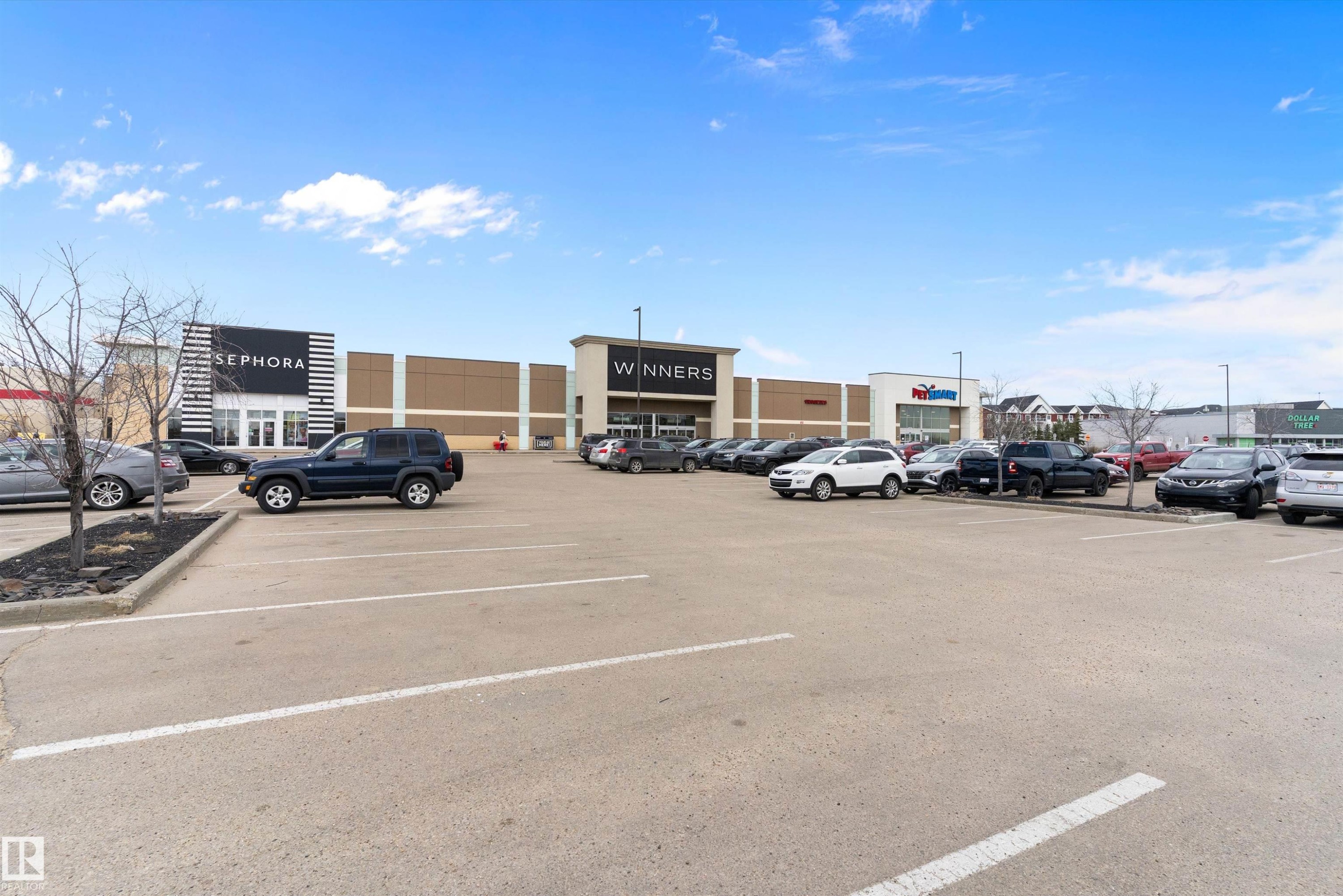 Large commercial parking lot with multiple retail storefronts visible - 3314 9 Street Nw, Edmonton, AB - Outdoor