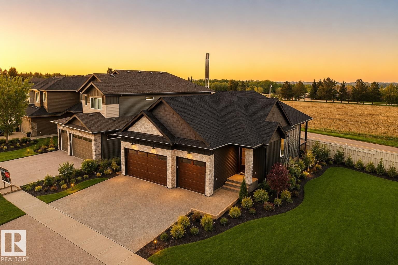 Contemporary exterior with dark siding, stone accents, and a dual garage featuring wood-finish doors - 149 Eastgate Way, St. Albert, AB - Outdoor