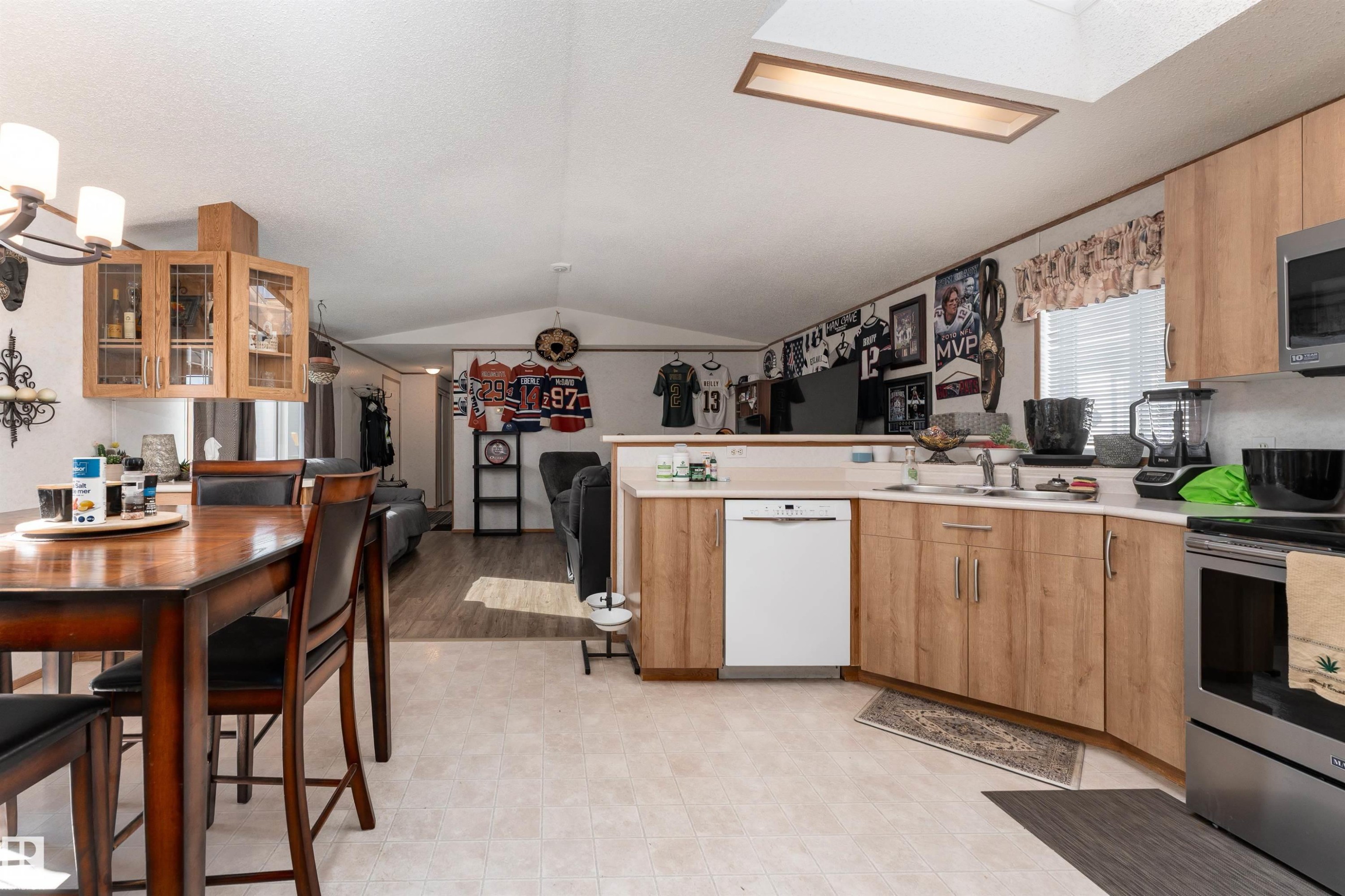 The kitchen features light wood cabinetry, a white dishwasher, and stainless steel appliances - 1663 Jubilee Crescent, Sherwood Park, AB - Indoor Photo Showing Other Room