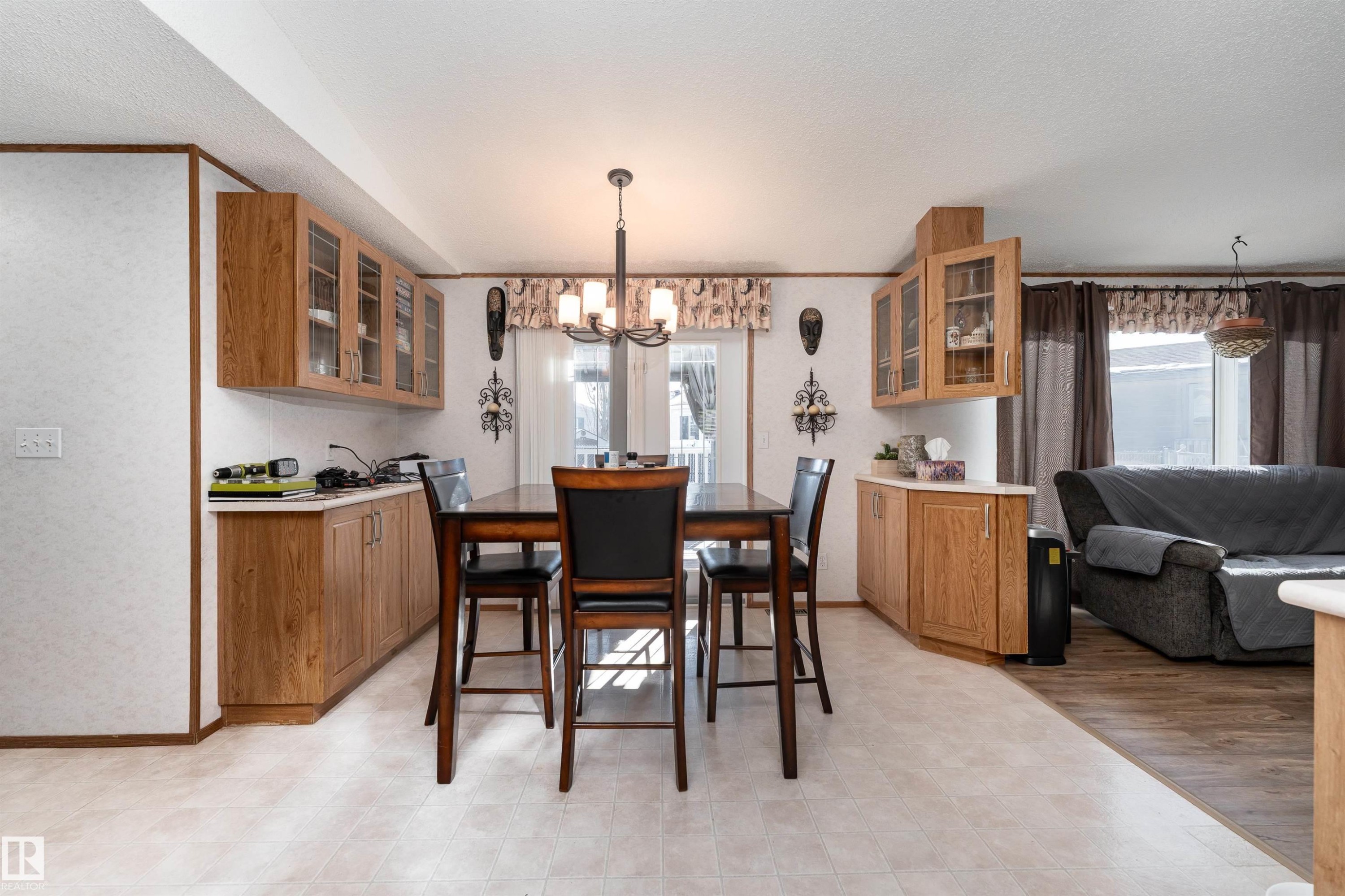 Open concept dining area featuring a dining table with chairs, an overhead chandelier, and built-in cabinetry with display features - 1663 Jubilee Crescent, Sherwood Park, AB - Indoor