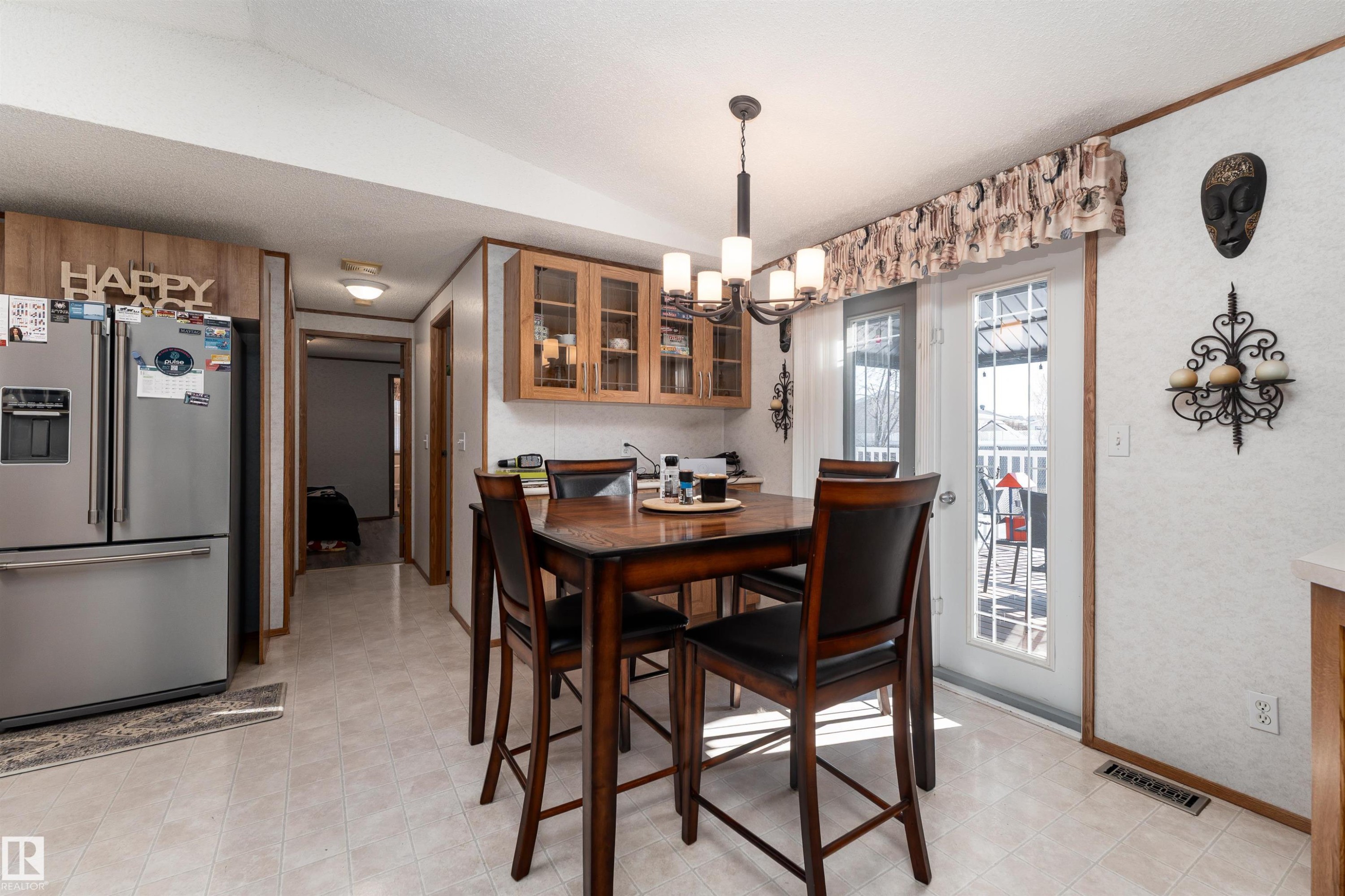 The dining area features a dark wood table and chairs, light-colored flooring, and a chandelier with multiple lights - 1663 Jubilee Crescent, Sherwood Park, AB - Indoor Photo Showing Dining Room