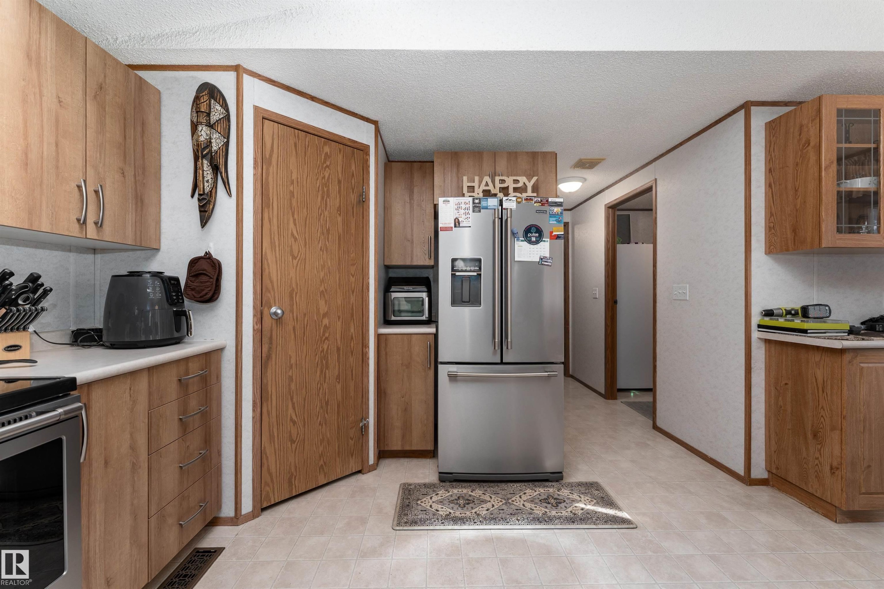 The kitchen features wood-look cabinetry, light-colored countertops, and a stainless steel refrigerator - 1663 Jubilee Crescent, Sherwood Park, AB - Indoor Photo Showing Kitchen