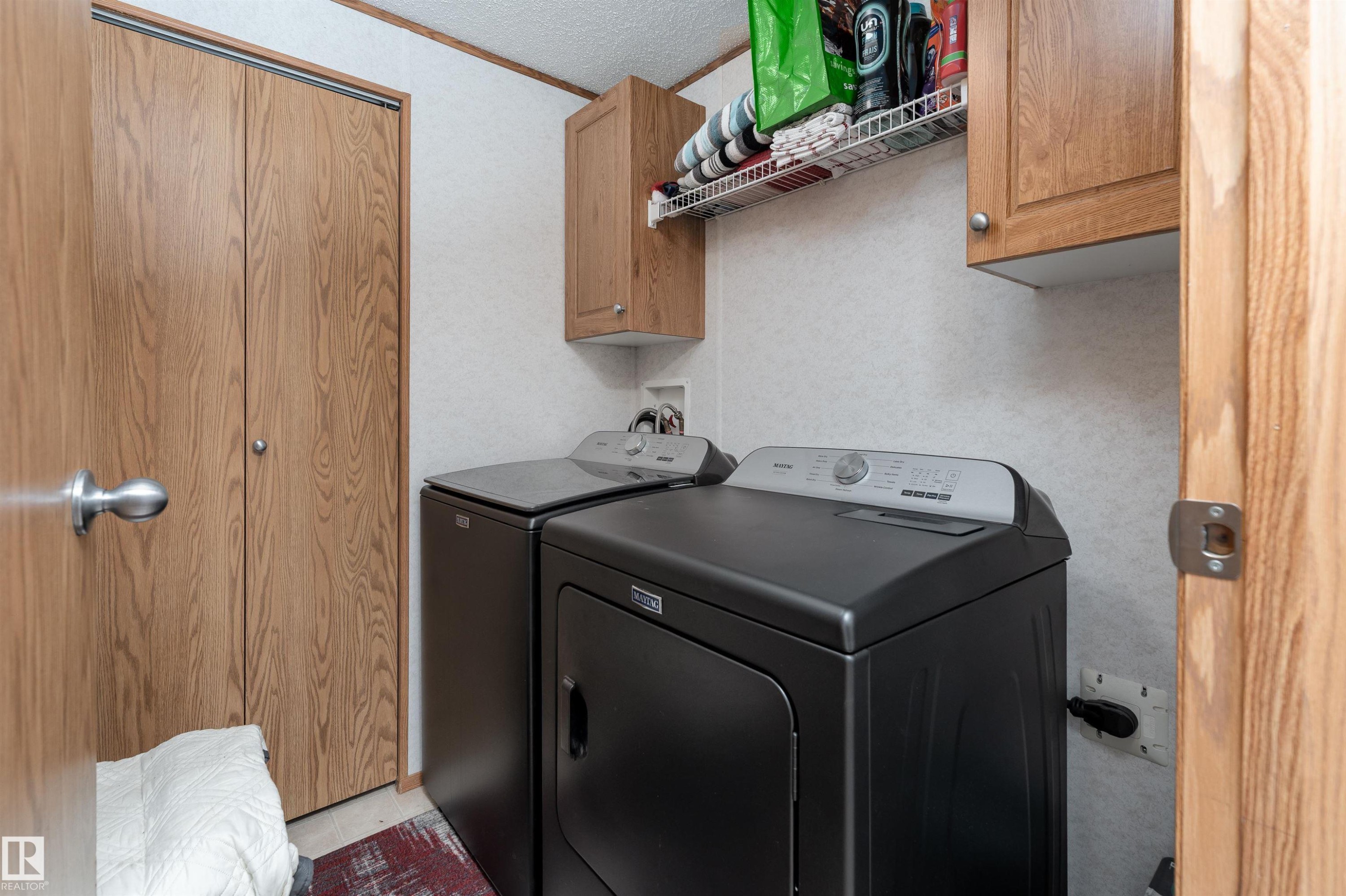 Utility area featuring a washer and dryer, wood-look cabinetry, and a wire shelf for storage - 1663 Jubilee Crescent, Sherwood Park, AB - Indoor Photo Showing Laundry Room
