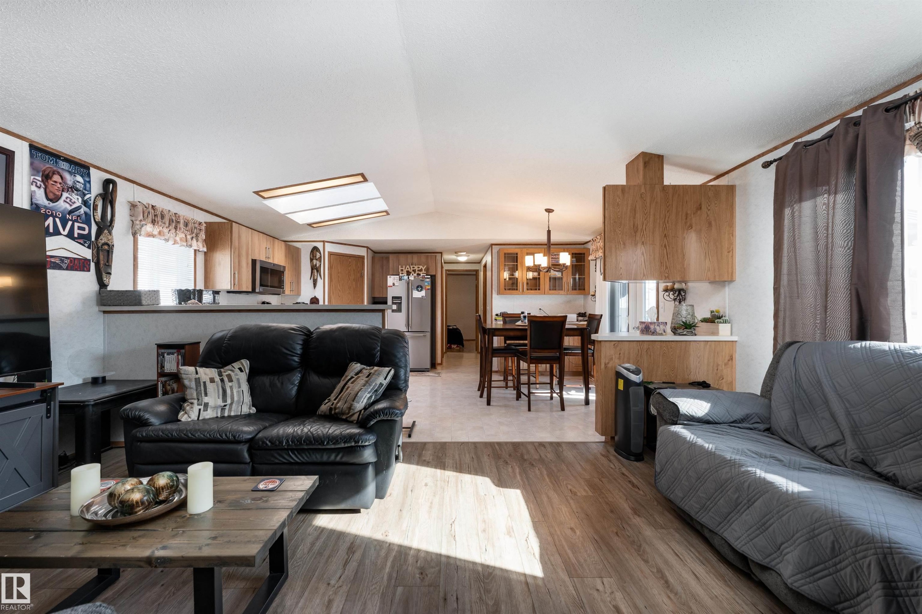 The living area features wood-look flooring and recessed lighting, with a view towards the dining area and kitchen - 1663 Jubilee Crescent, Sherwood Park, AB - Indoor Photo Showing Living Room