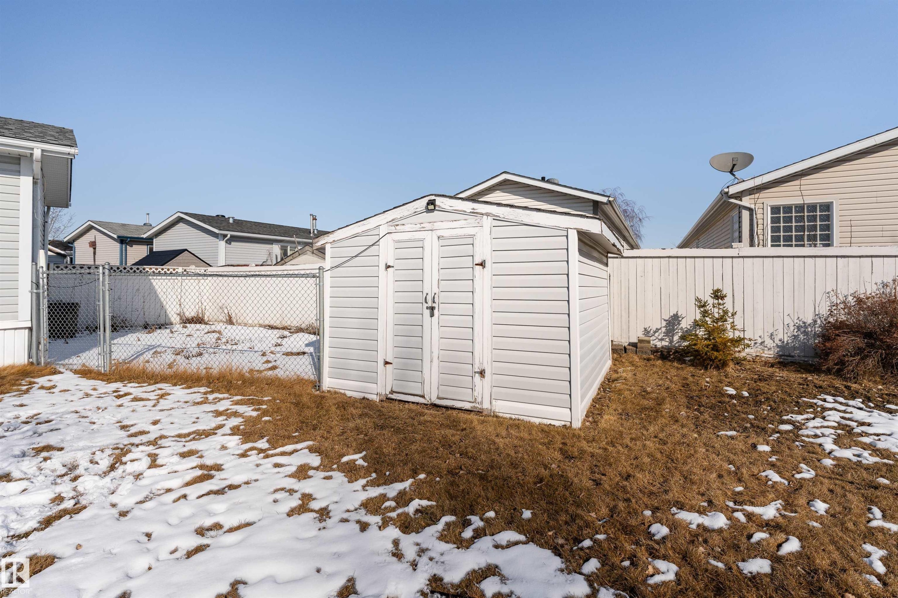 The property features a white outdoor storage shed with double doors, set within a fenced yard - 1663 Jubilee Crescent, Sherwood Park, AB - Outdoor