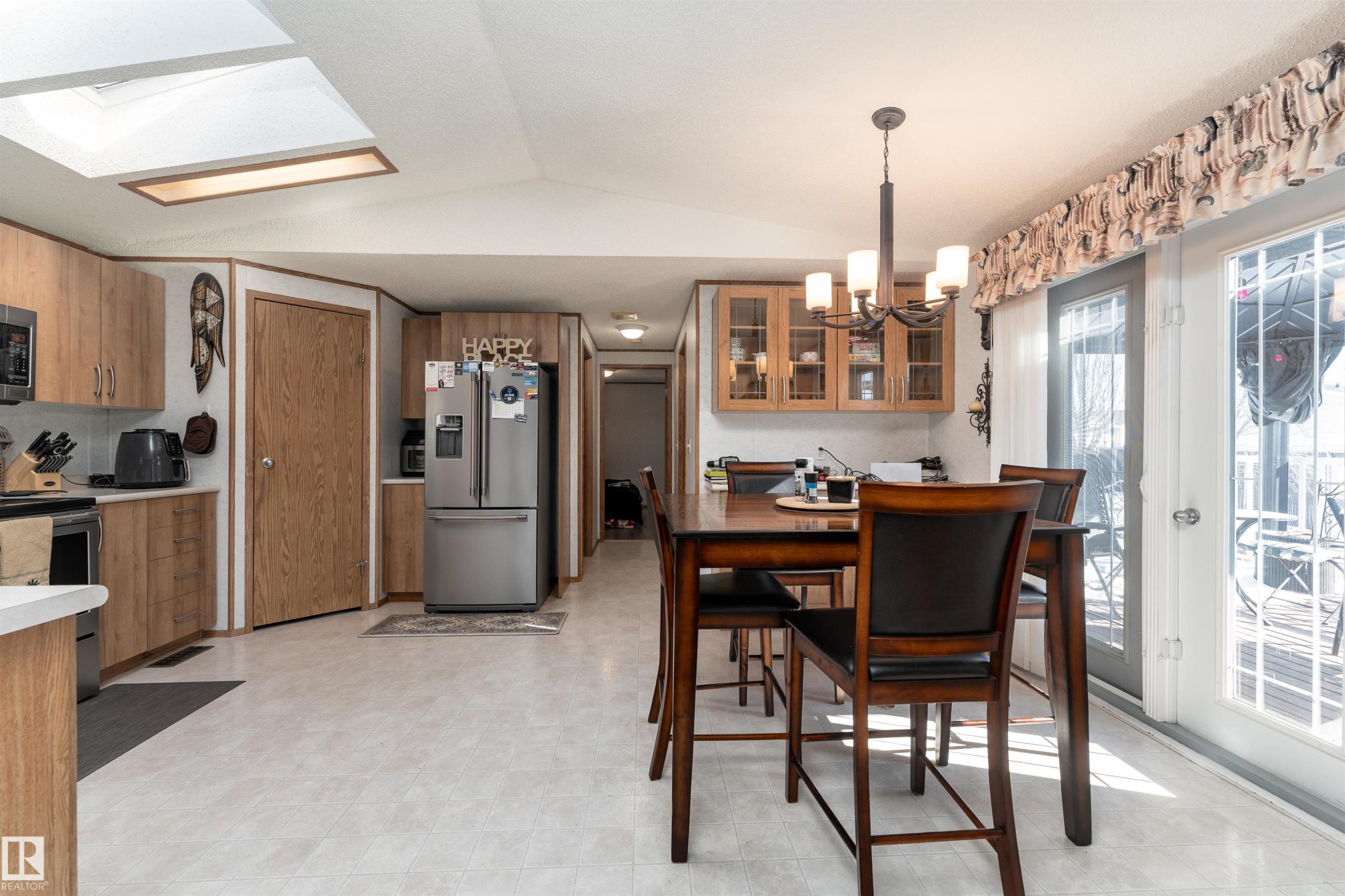 Open concept living area with light wood cabinetry, a skylight, and double doors providing access to the outdoors - 1663 Jubilee Crescent, Sherwood Park, AB - Indoor