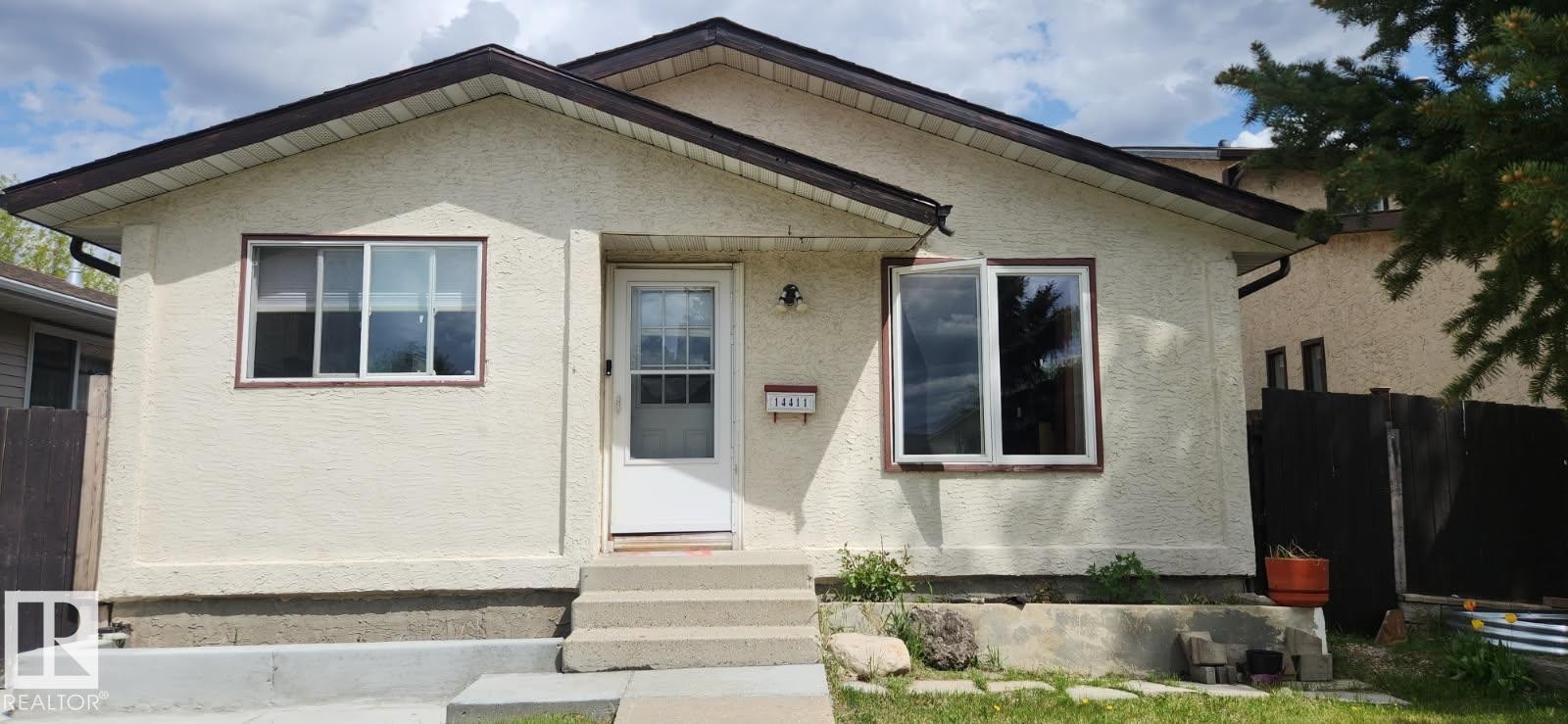 Stucco exterior featuring contrasting trim, a gabled roofline, and multiple windows - 14411 31 Street, Edmonton, AB - Outdoor With Exterior