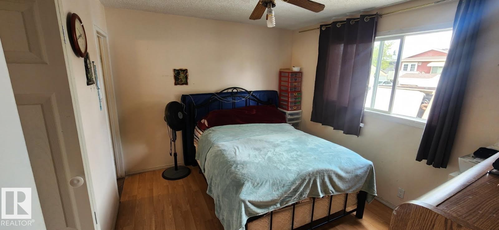 Bedroom featuring wood-finish flooring, a ceiling fan with integrated lighting, and a window with dark curtain panels - 14411 31 Street, Edmonton, AB - Indoor Photo Showing Bedroom