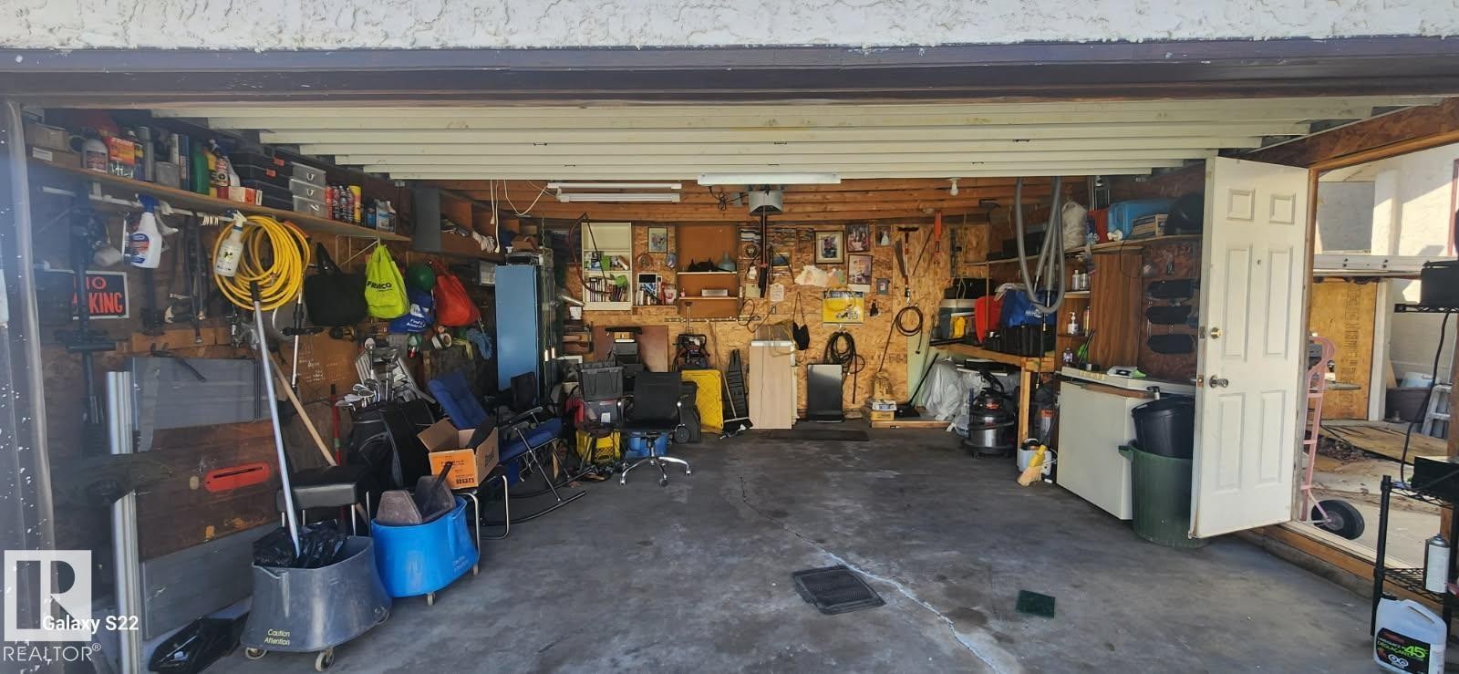 Garage space with concrete flooring, exposed wooden beams, and an overhead garage door - 14411 31 Street, Edmonton, AB - Indoor Photo Showing Garage