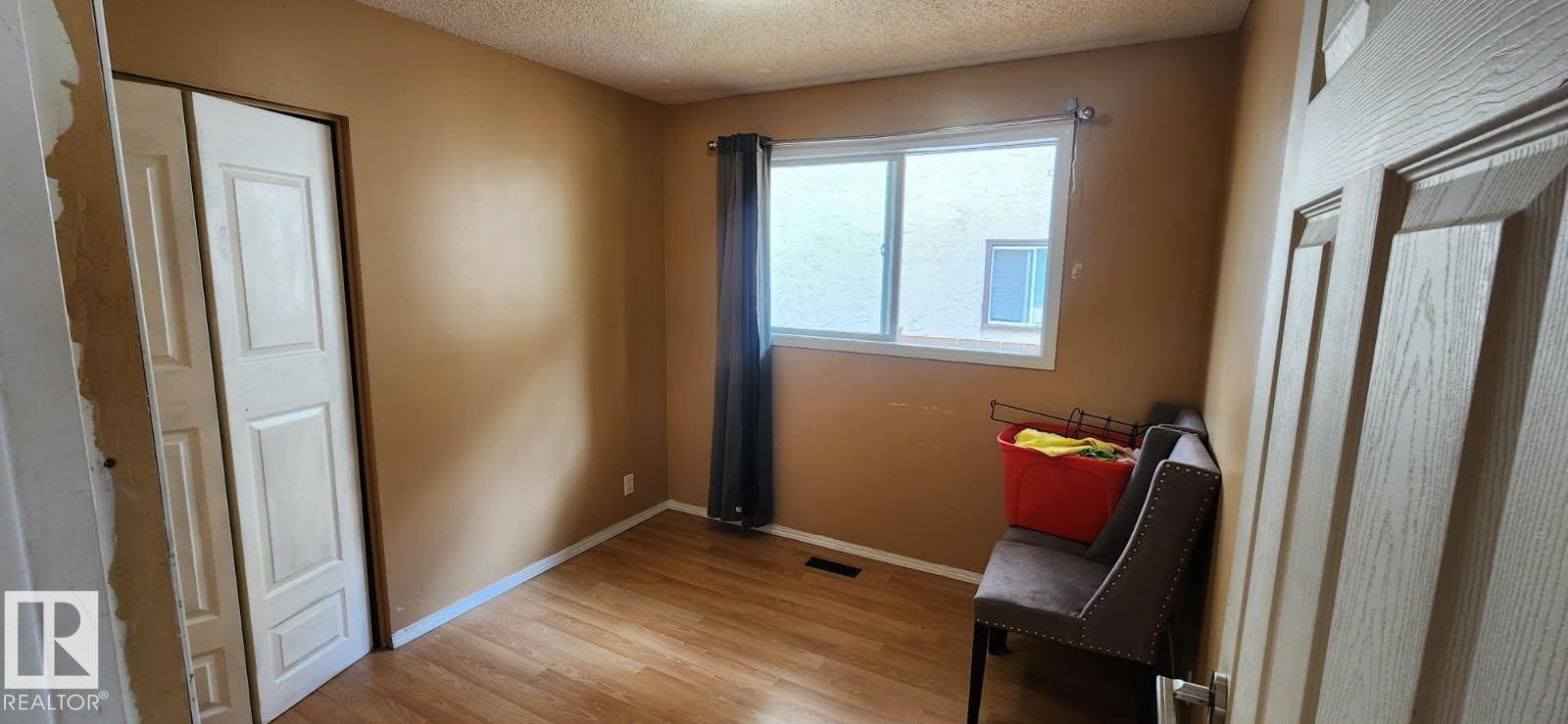 Room featuring wood-finish flooring, a double-pane window with dark curtains, and a textured ceiling - 14411 31 Street, Edmonton, AB - Indoor Photo Showing Other Room
