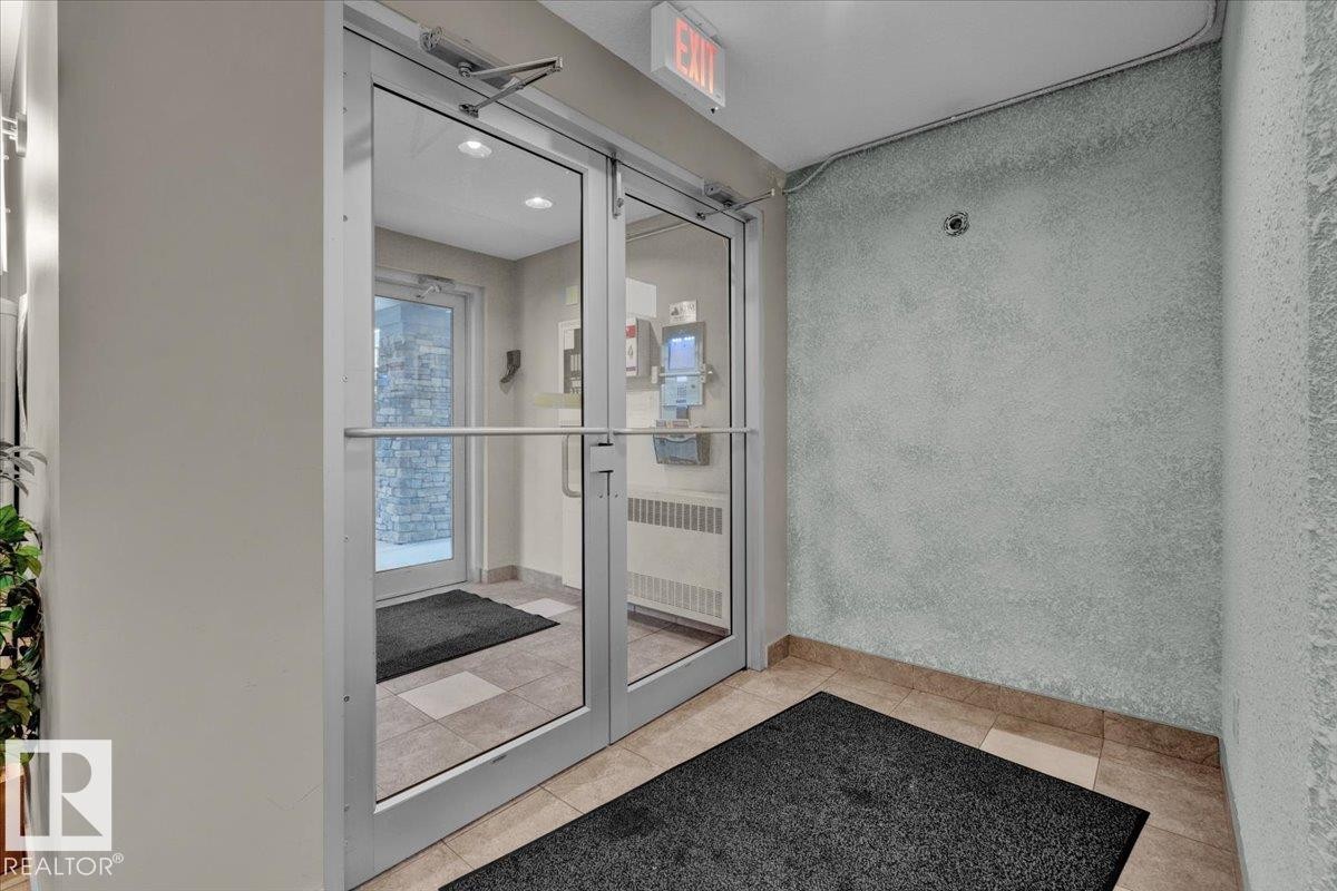 Glass double doors with aluminum frames, recessed ceiling lighting, and a prominent "EXIT" sign above - 326 6076 Schonsee Way, Edmonton, AB - Indoor Photo Showing Other Room