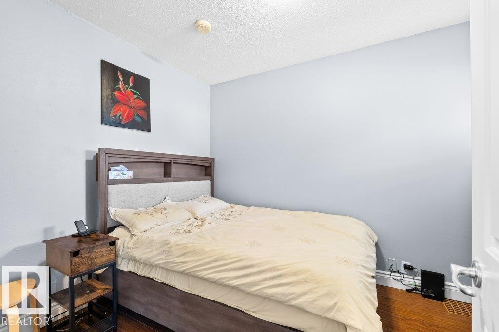 Bedroom featuring light blue walls, wood-finish flooring, and a textured white ceiling - 12207 110 Avenue, Edmonton, AB - Indoor Photo Showing Bedroom