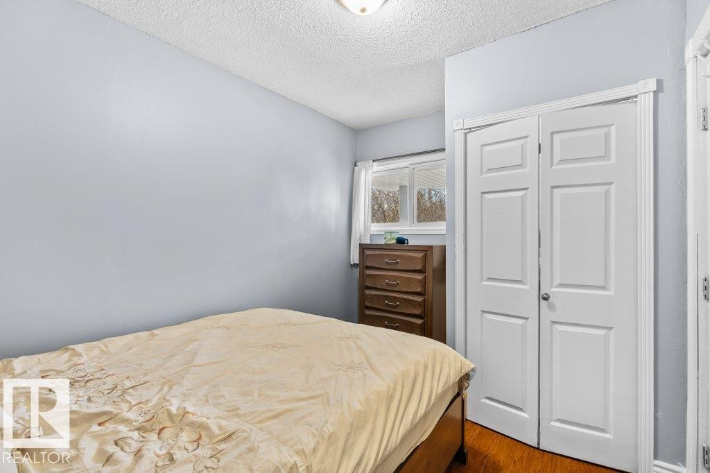 Interior room featuring light blue painted walls, wood-finish flooring, and a white bi-fold closet door - 12207 110 Avenue, Edmonton, AB - Indoor Photo Showing Bedroom