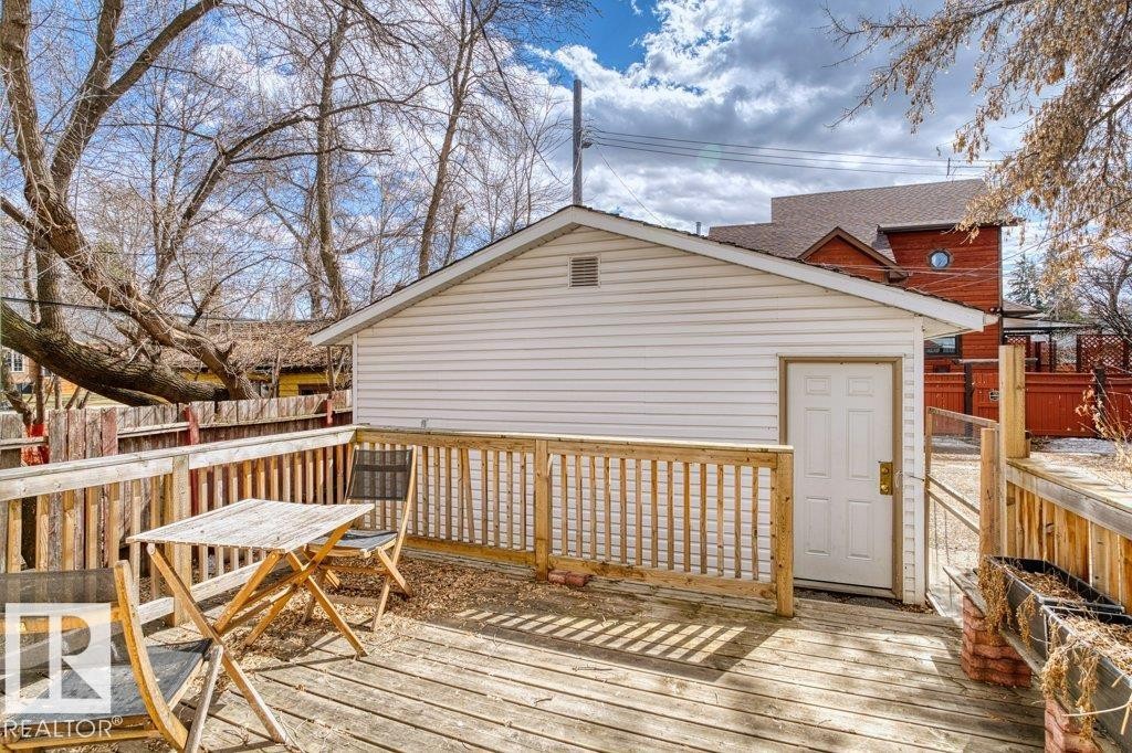 Spacious wooden deck featuring a white paneled outbuilding with a gable roof, privacy fencing, and mature trees - 12207 110 Avenue, Edmonton, AB - Outdoor With Deck Patio Veranda With Exterior