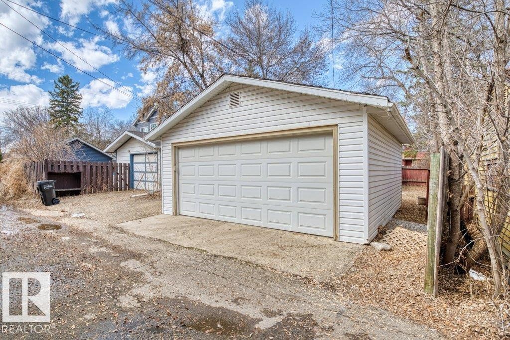 Detached garage featuring a paneled overhead door and white vinyl siding - 12207 110 Avenue, Edmonton, AB - Outdoor