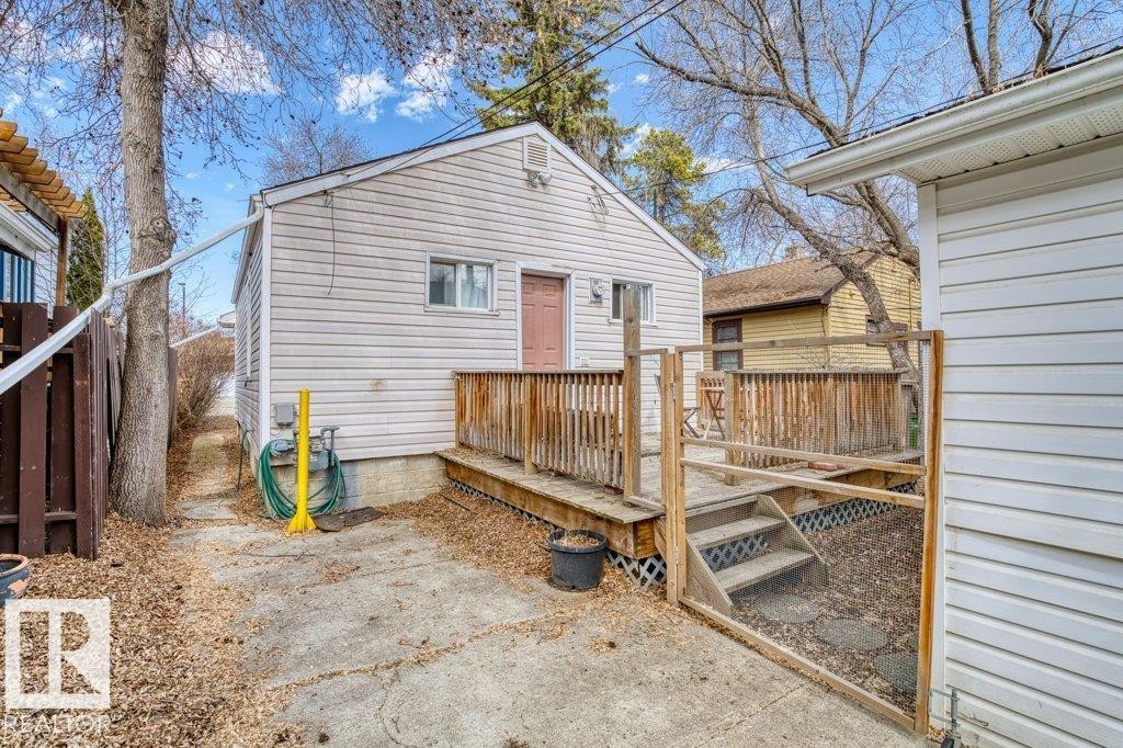 Rear exterior featuring light-colored siding, a brown door, and a multi-level wood deck with steps - 12207 110 Avenue, Edmonton, AB - Outdoor With Exterior