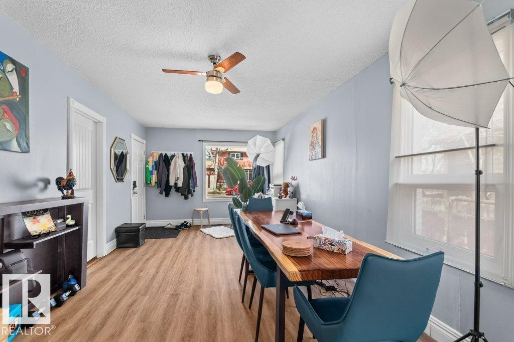 Open-concept interior featuring wood-finish flooring, a ceiling fan with integrated lighting, and multiple windows with roller shades - 12207 110 Avenue, Edmonton, AB - Indoor Photo Showing Dining Room