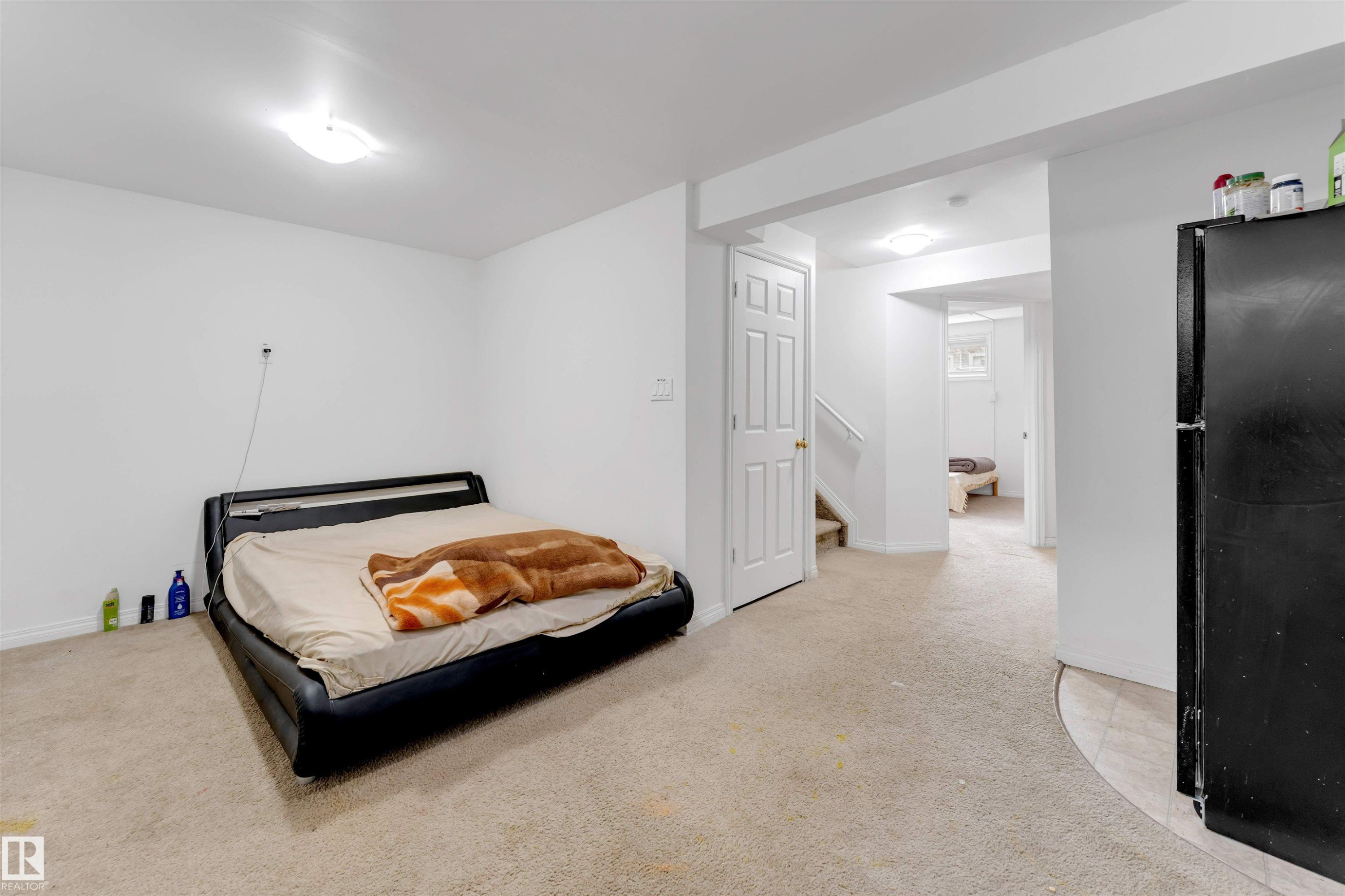 Carpeted room with white walls, overhead ceiling light fixture, and a segmented doorway leading to a staircase and additional interior space - 48 2503 24 Street, Edmonton, AB - Indoor Photo Showing Bedroom