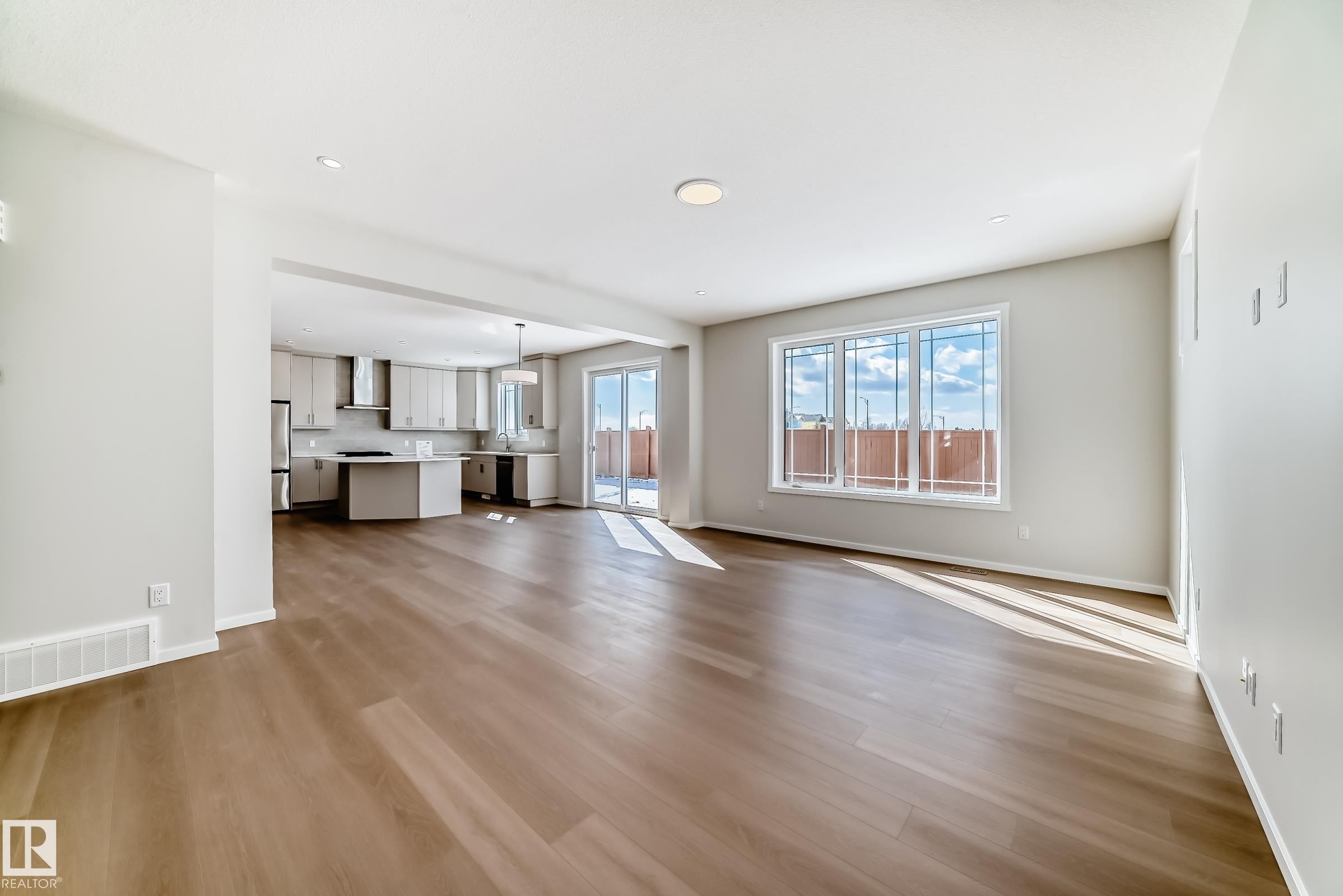 Open concept living area featuring hardwood style flooring, recessed lighting, and large windows providing natural light - 1516 206 Street Nw, Edmonton, AB - Indoor Photo Showing Other Room