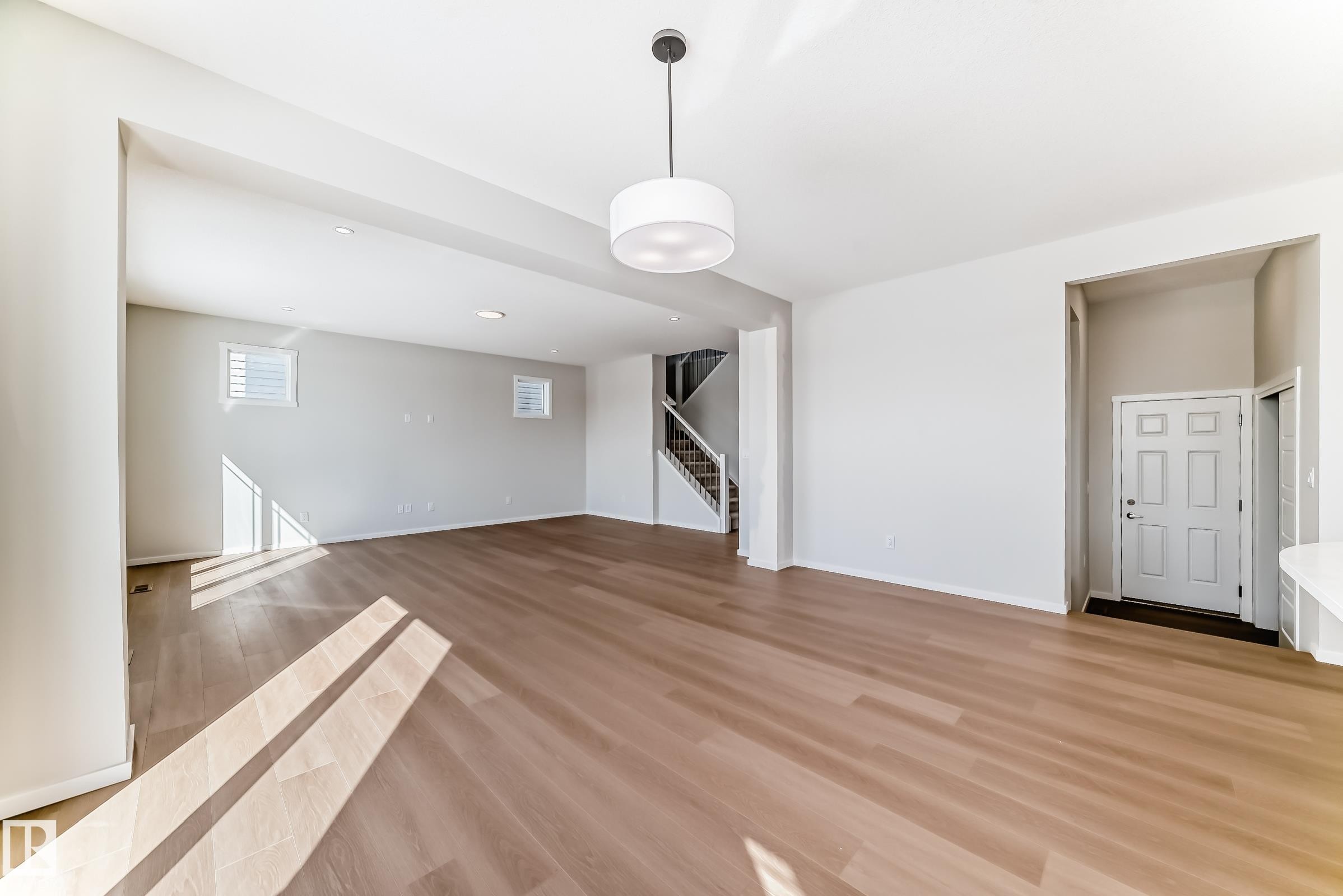 Spacious interior with light wood flooring, white walls, and a contemporary ceiling light fixture - 1516 206 Street Nw, Edmonton, AB - Indoor Photo Showing Other Room