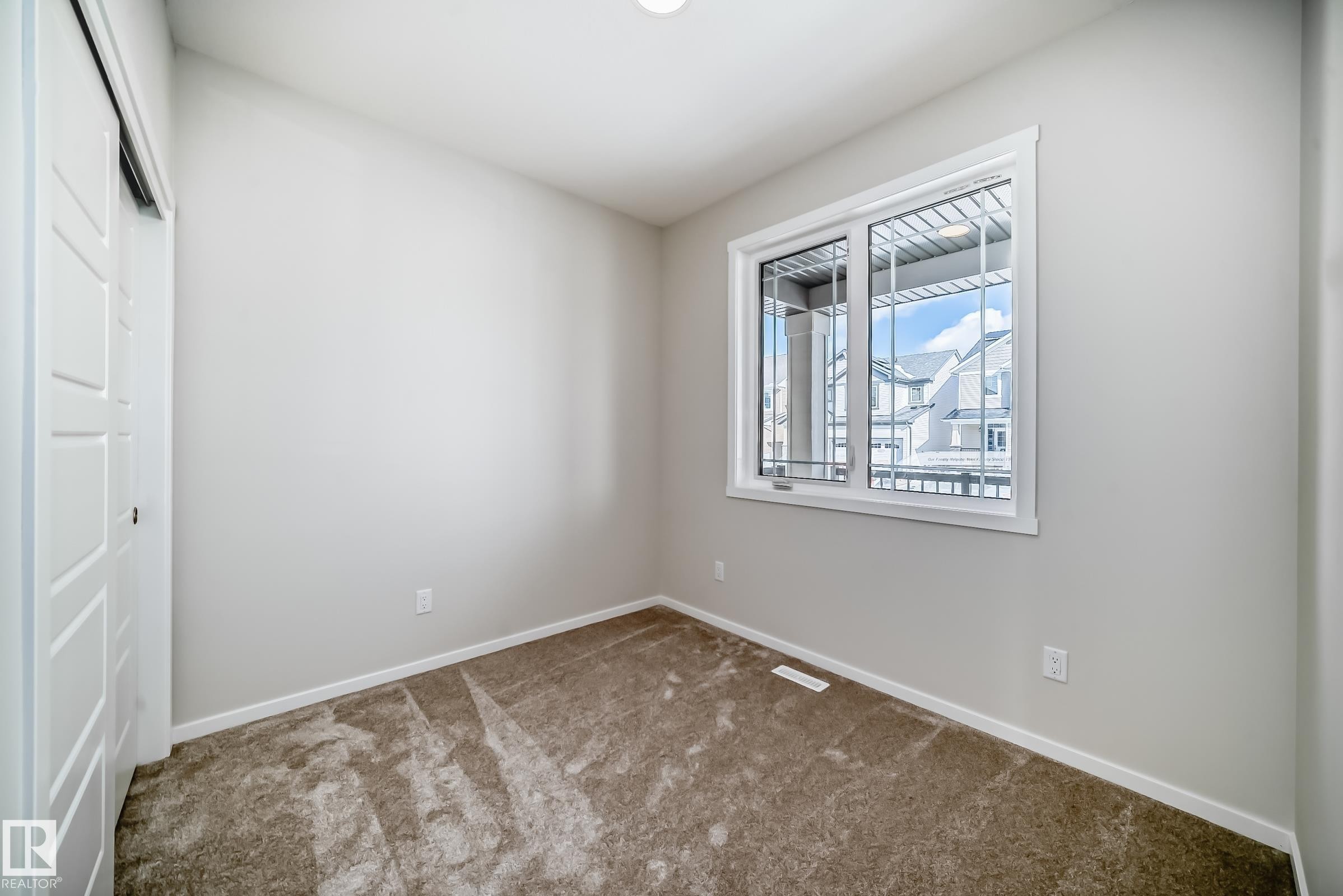 This room features neutral-toned walls, brown carpet, and a window with white trim - 1516 206 Street Nw, Edmonton, AB - Indoor Photo Showing Other Room