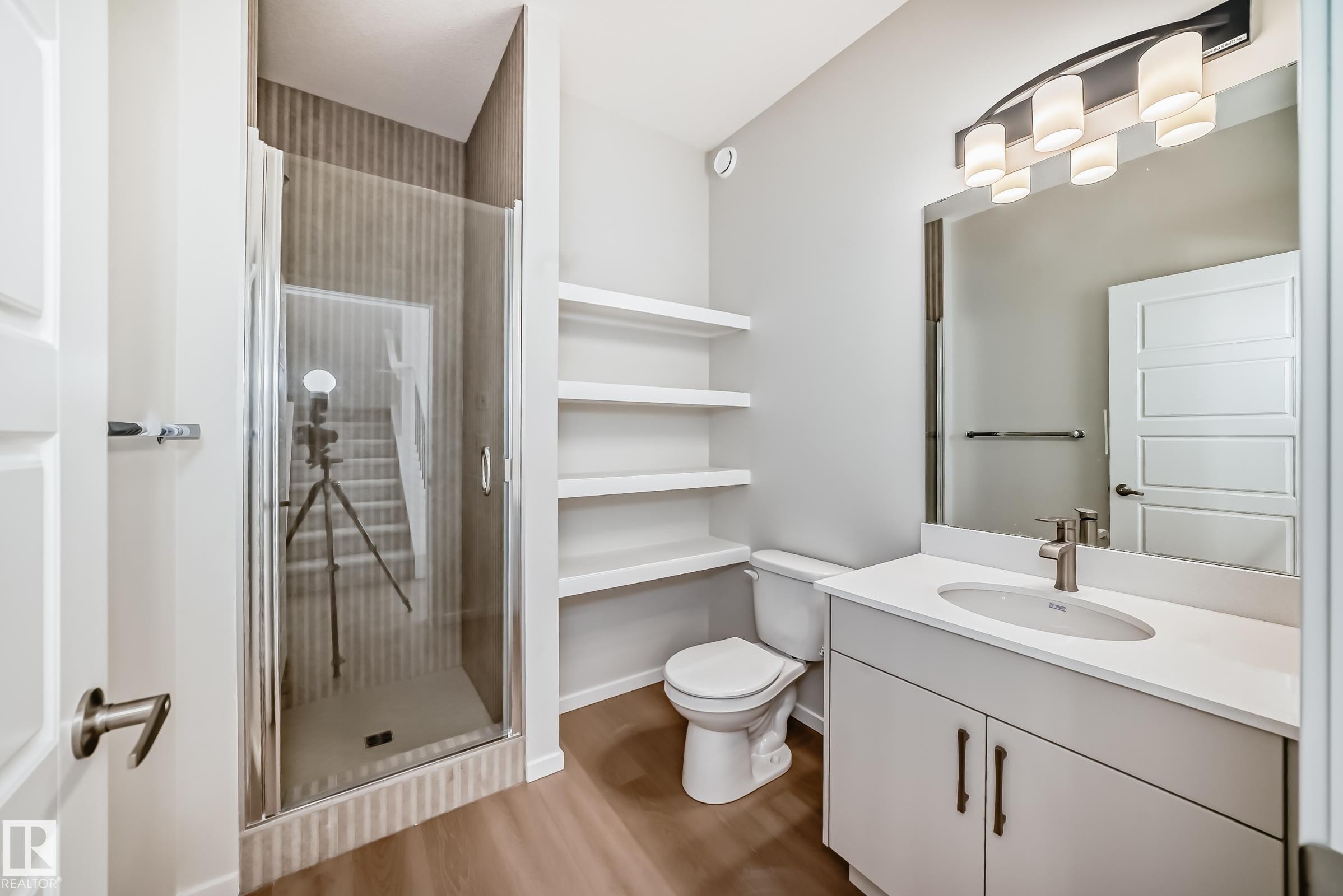 The bathroom features a modern vanity with a white countertop and an undermount sink, a shower with a glass enclosure, and white floating shelves for storage - 1516 206 Street Nw, Edmonton, AB - Indoor Photo Showing Bathroom