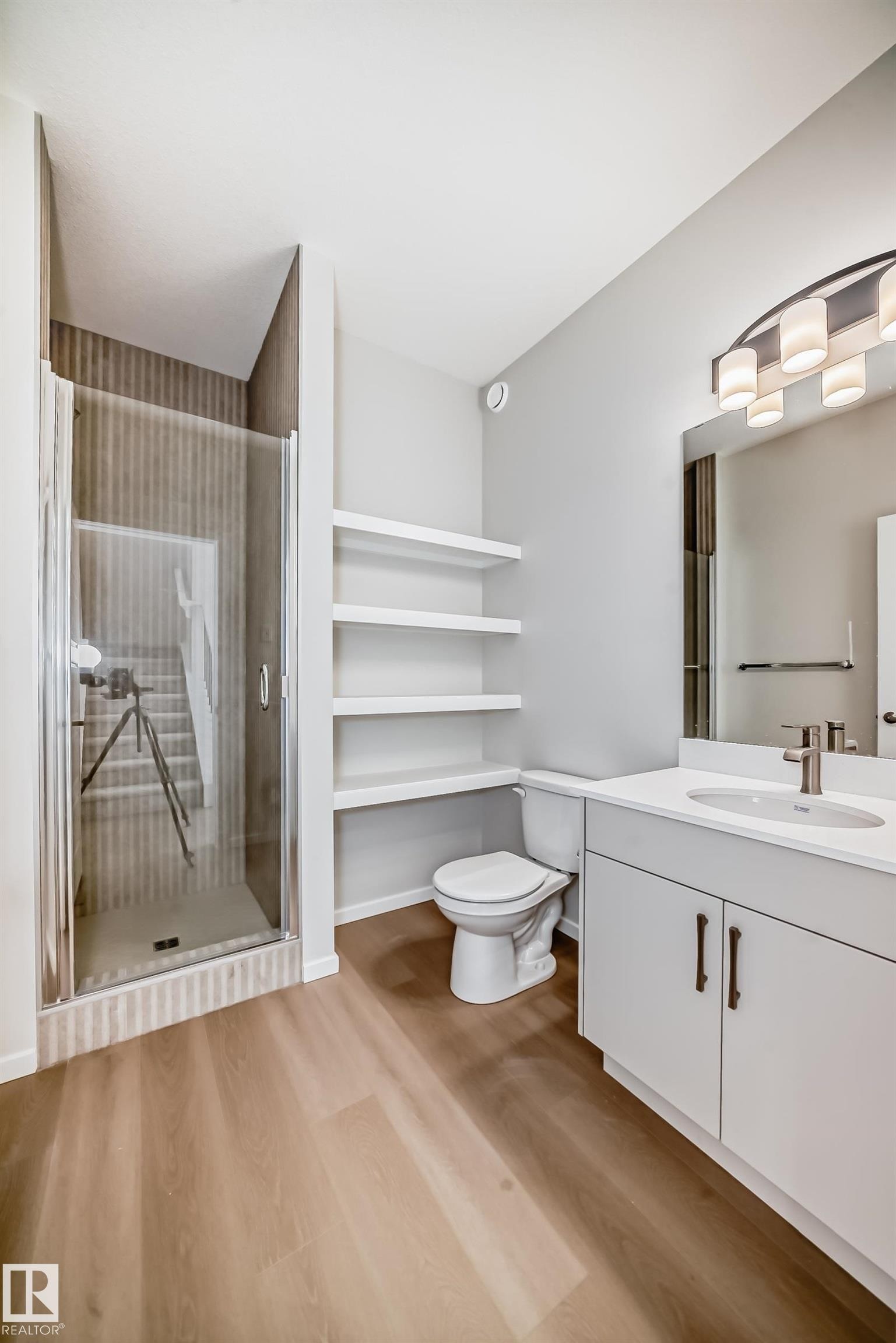 This bathroom features a glass-enclosed shower with textured wall tiles, a vanity with a white countertop and a rectangular sink, and light-toned flooring - 1516 206 Street Nw, Edmonton, AB - Indoor Photo Showing Bathroom
