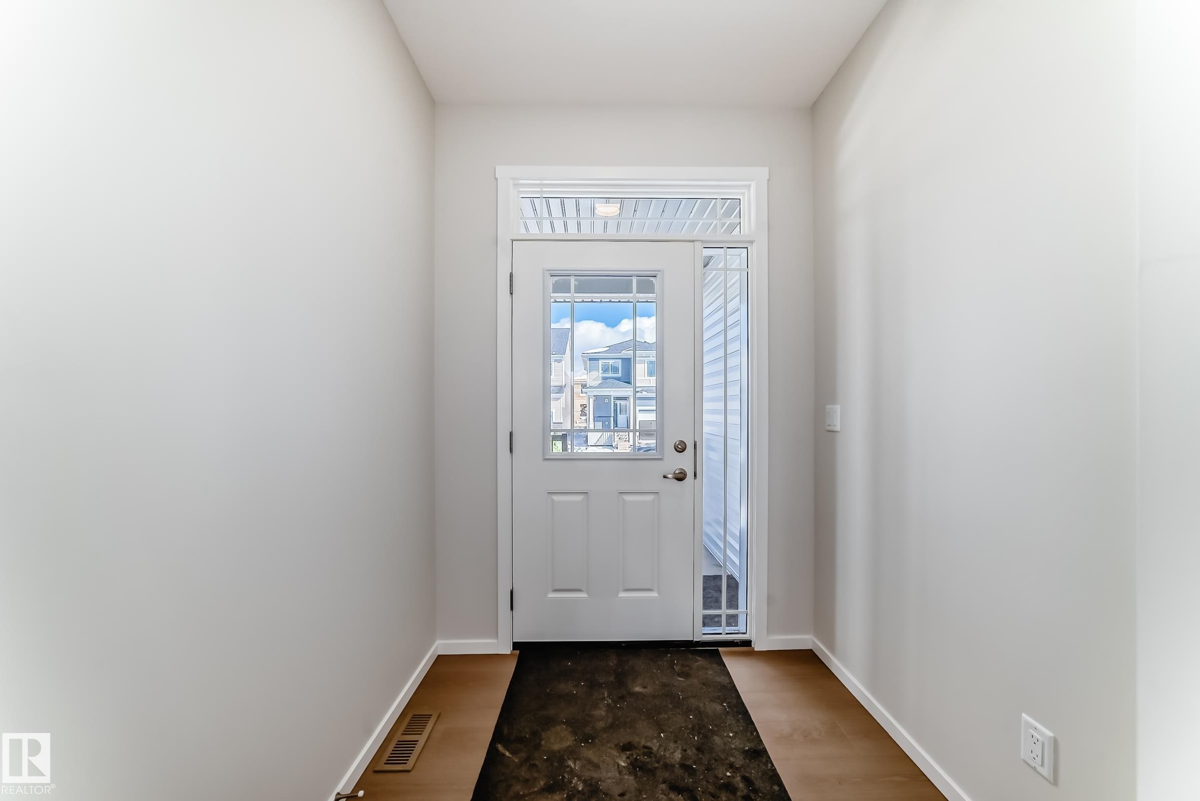 Entryway featuring hardwood style flooring, light-colored walls, and a white door with glass panels and a transom window - 1516 206 Street Nw, Edmonton, AB - Indoor Photo Showing Other Room