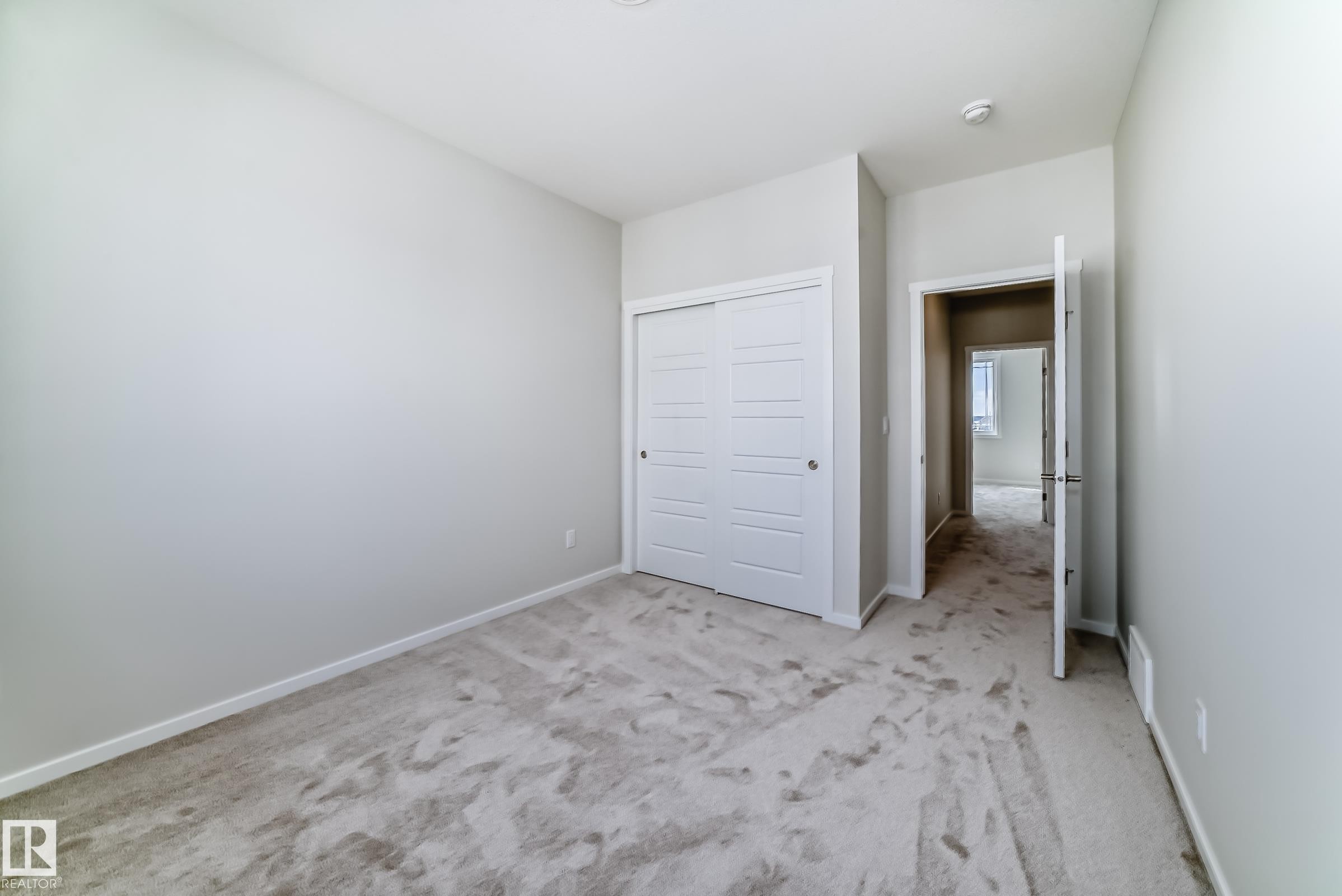 Room featuring light-colored walls, carpeted flooring, and a closet with white bi-fold doors - 1516 206 Street Nw, Edmonton, AB - Indoor