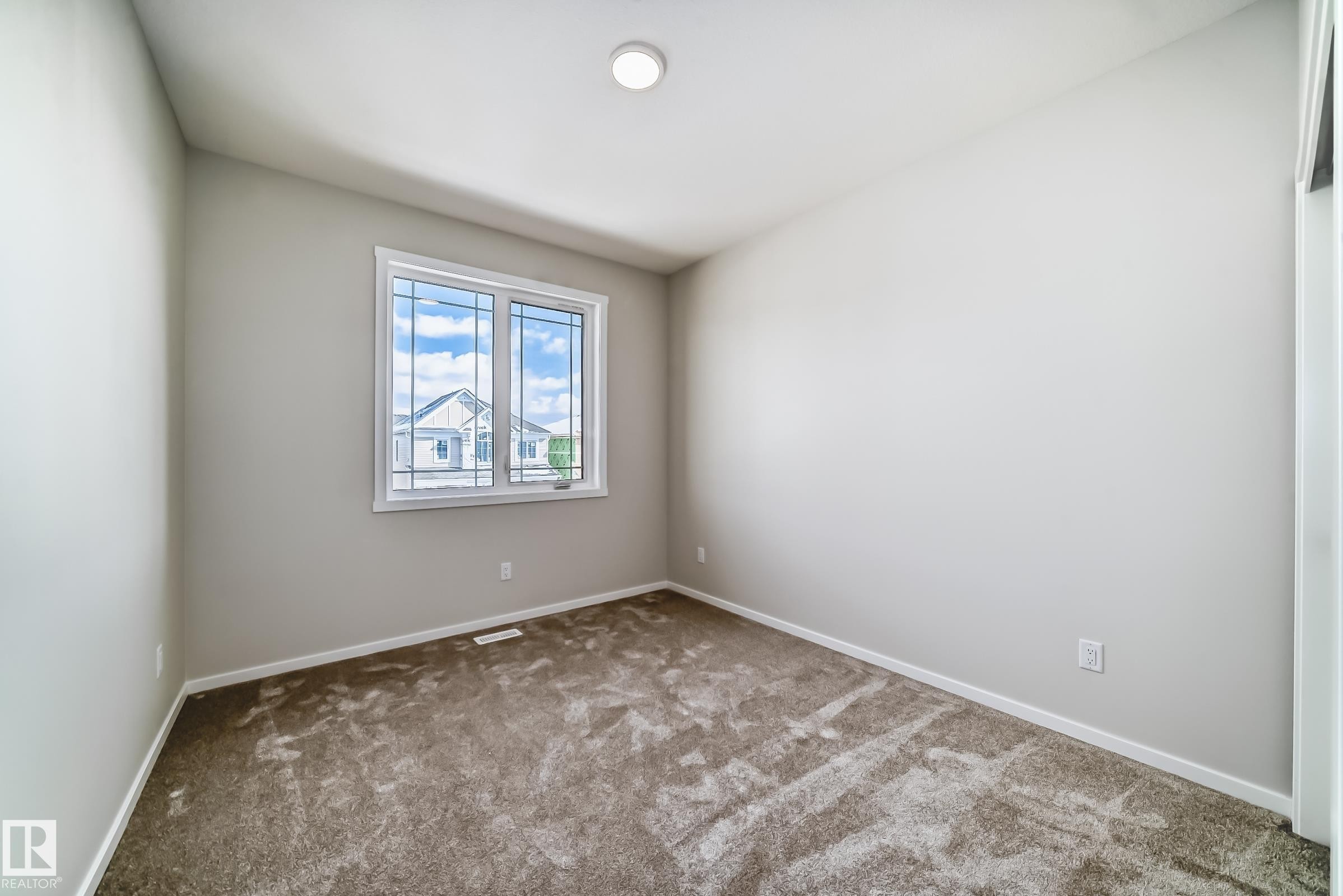 This room features light-colored walls, patterned carpet flooring, and a window with white trim - 1516 206 Street Nw, Edmonton, AB - Indoor Photo Showing Other Room