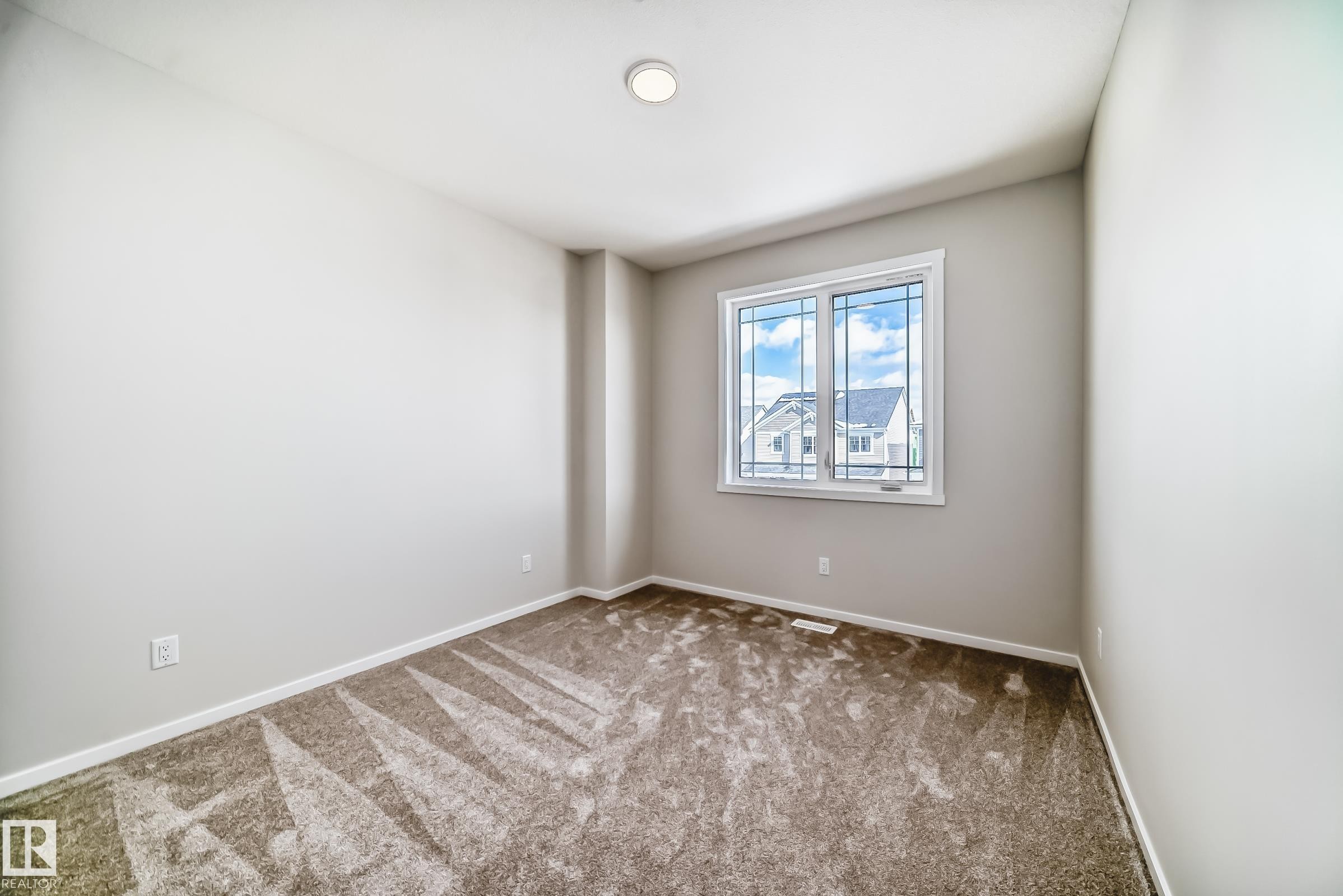 This room features neutral-toned walls, a window with white trim, and a ceiling light fixture - 1516 206 Street Nw, Edmonton, AB - Indoor Photo Showing Other Room