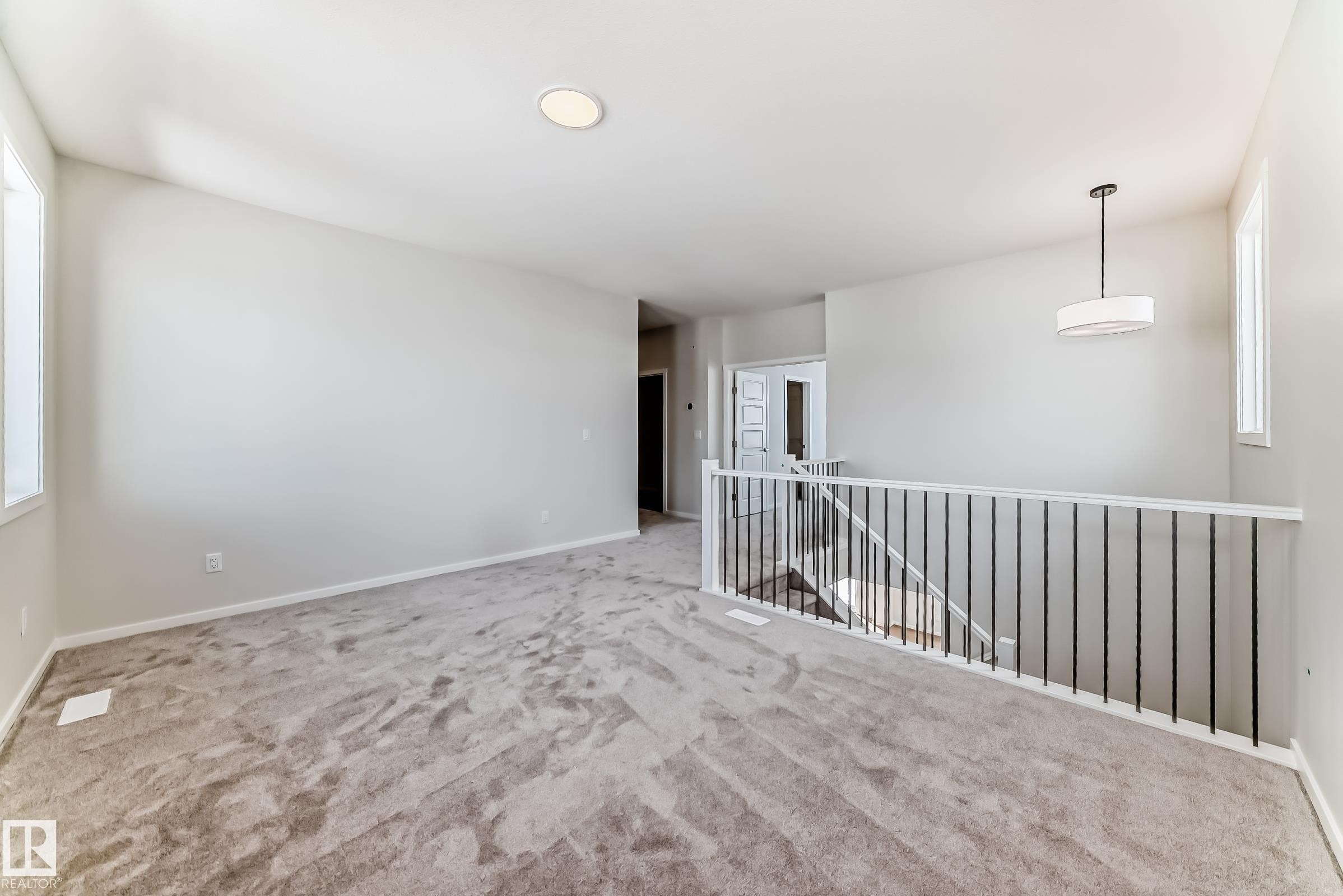 The property features a spacious room with carpet flooring, light-colored walls, and large windows providing natural light - 1516 206 Street Nw, Edmonton, AB - Indoor Photo Showing Other Room
