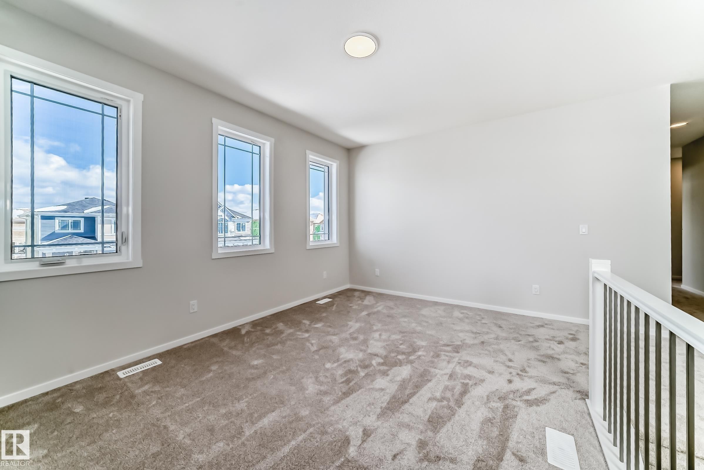 Inviting room with light neutral walls, gray carpet, and three windows providing natural light - 1516 206 Street Nw, Edmonton, AB - Indoor Photo Showing Other Room
