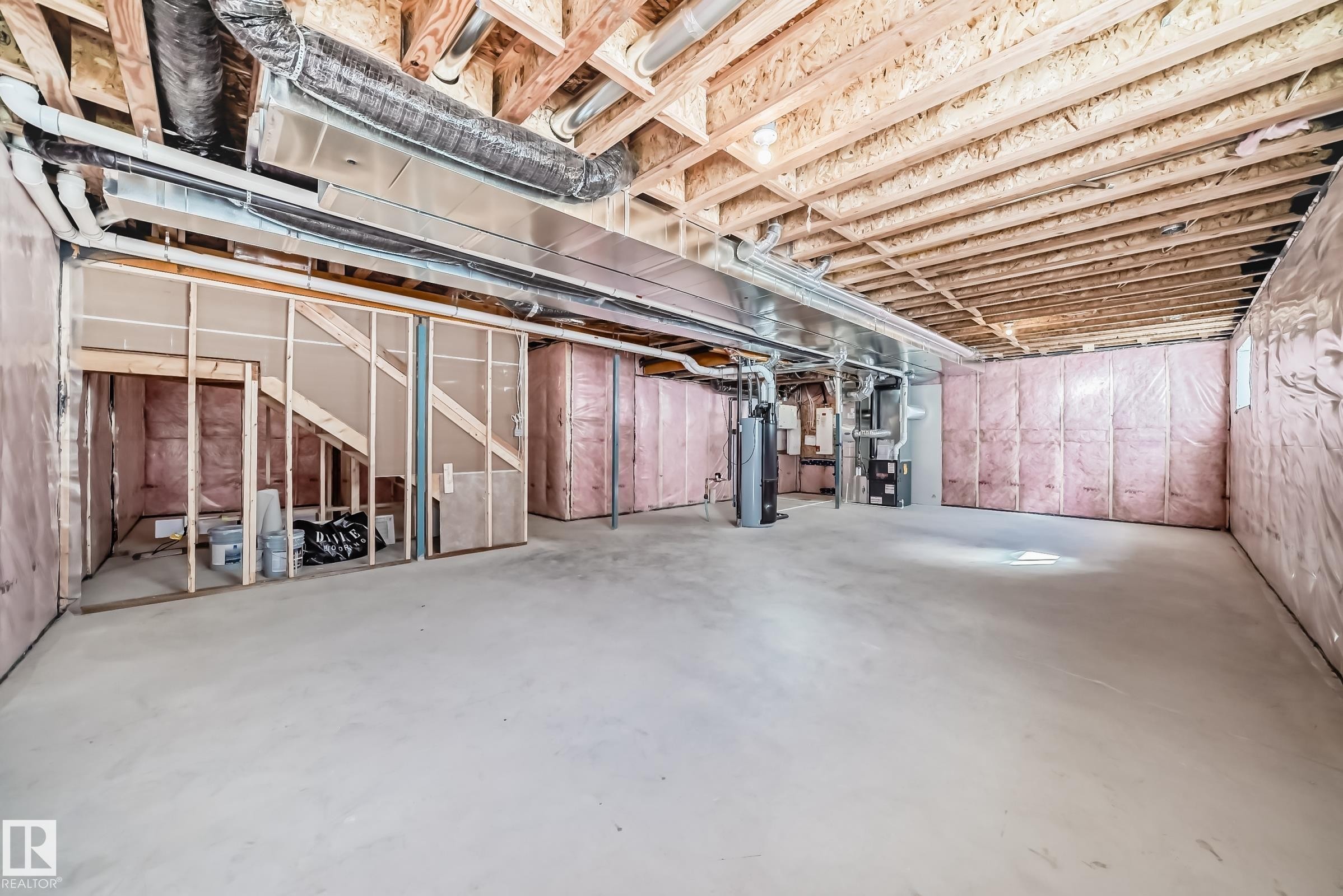 The unfinished basement provides an expansive space with exposed ceiling joists, insulation along the walls, and visible ductwork - 1516 206 Street Nw, Edmonton, AB - Indoor Photo Showing Basement