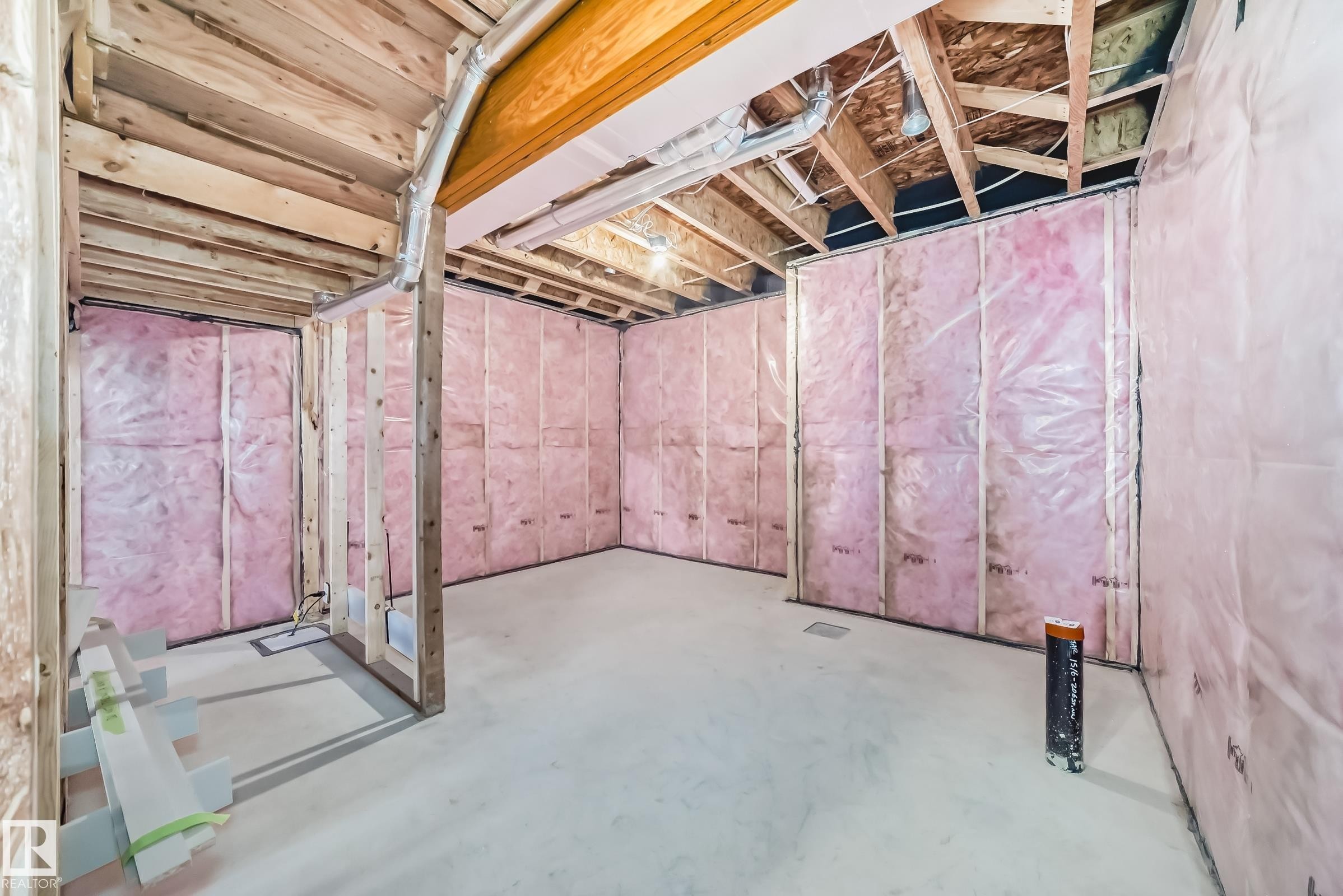 Unfinished interior space featuring exposed wooden beams, framed walls with pink insulation, and a concrete floor - 1516 206 Street Nw, Edmonton, AB - Indoor Photo Showing Basement