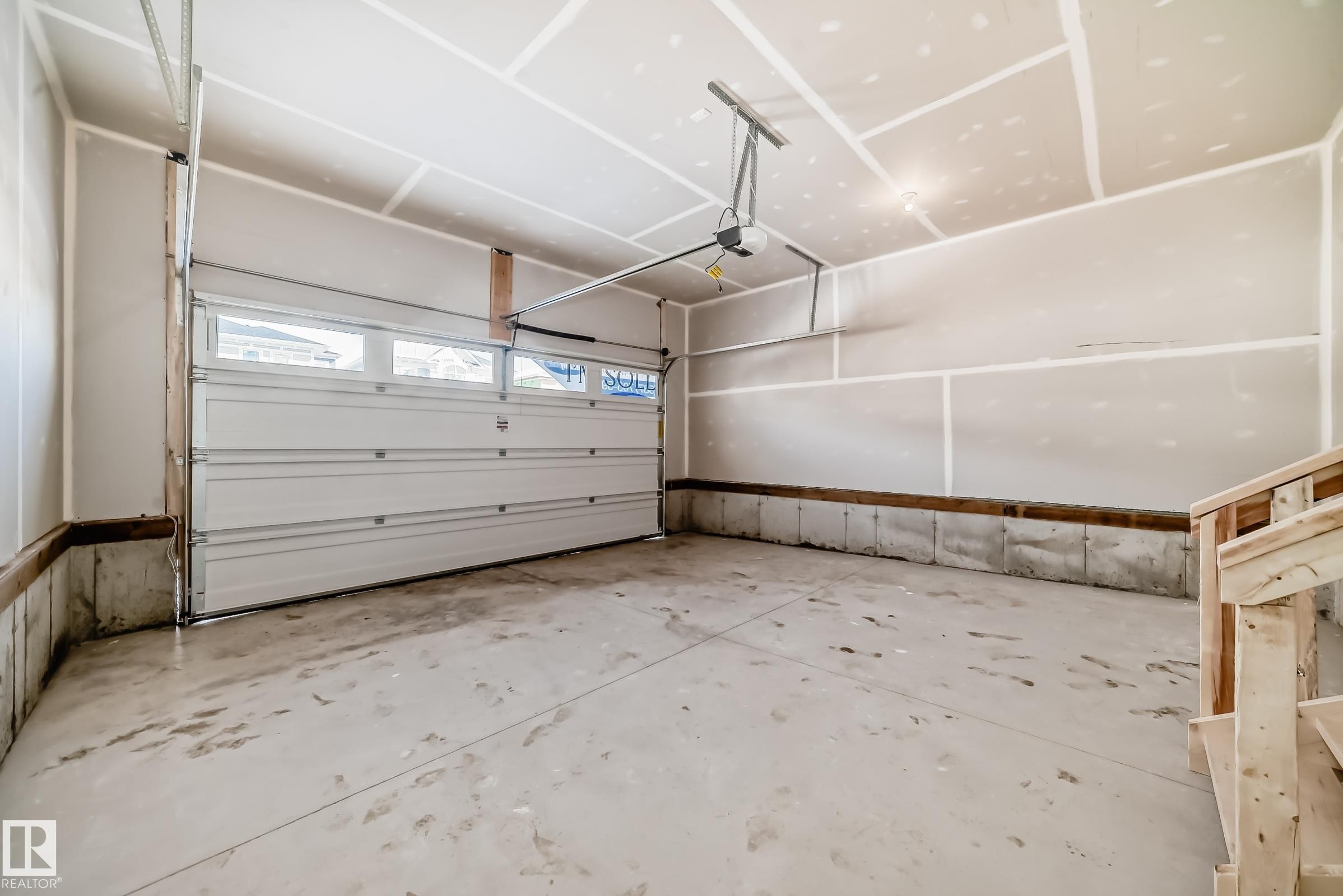 The garage features a concrete floor, a white overhead door with windows, and an automatic garage door opener - 1516 206 Street Nw, Edmonton, AB - Indoor Photo Showing Garage