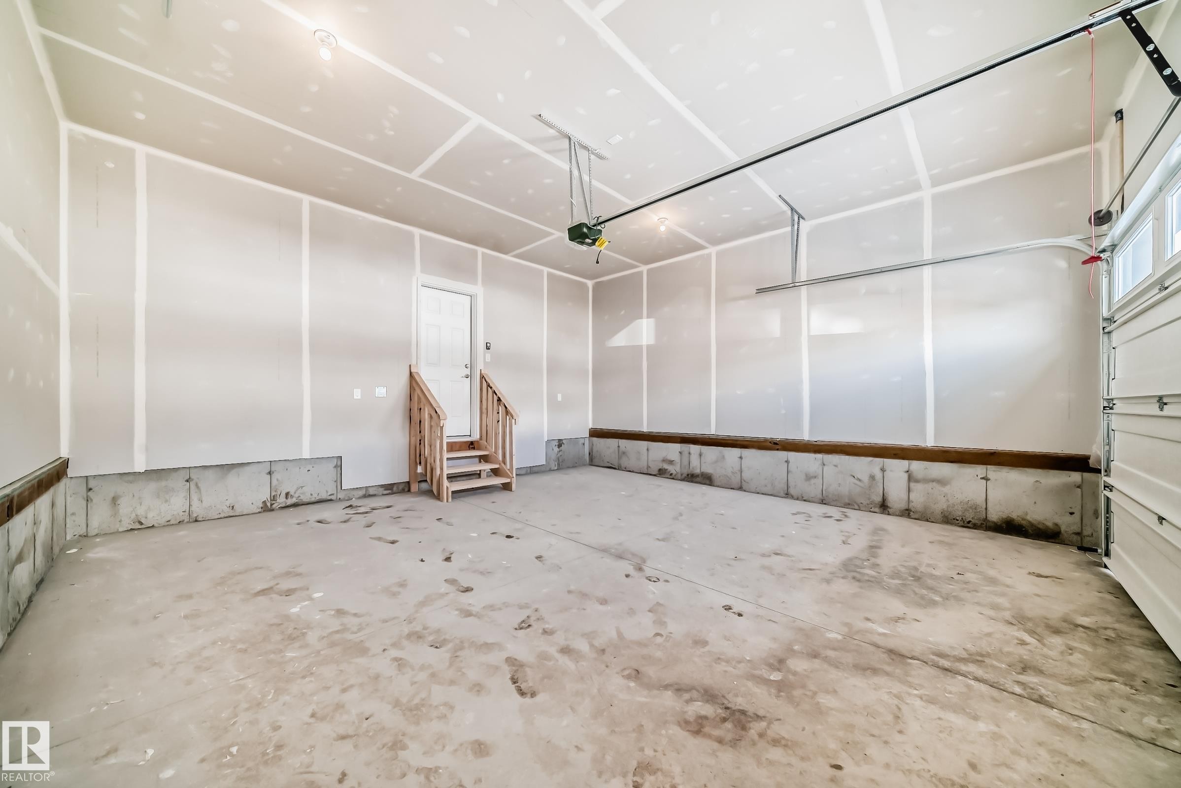 Spacious garage featuring a concrete floor, an overhead door, and a utility door with wooden steps - 1516 206 Street Nw, Edmonton, AB - Indoor Photo Showing Garage