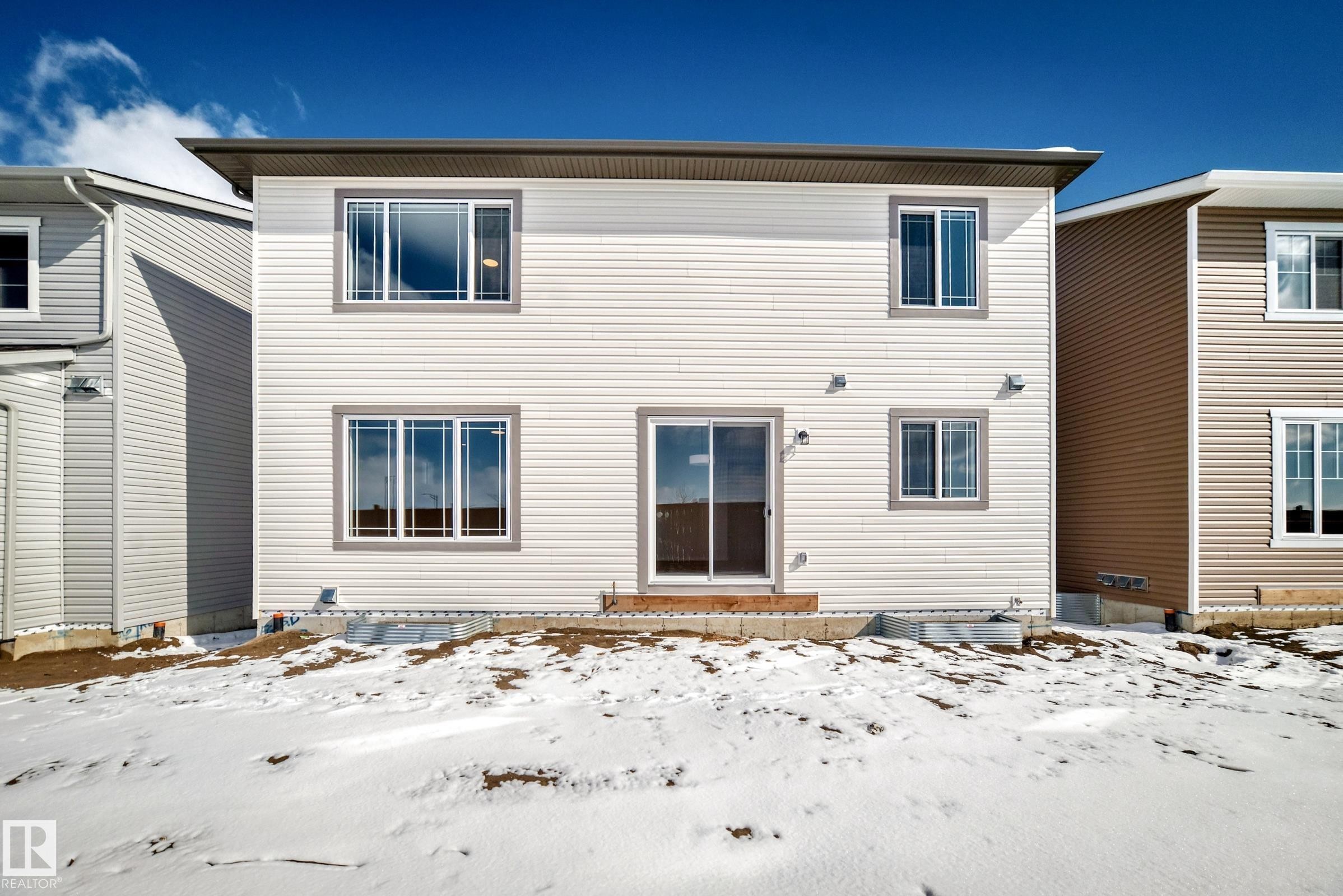 The property features light-colored horizontal siding, a dark roof, and a sliding glass patio door - 1516 206 Street Nw, Edmonton, AB - Outdoor With Exterior