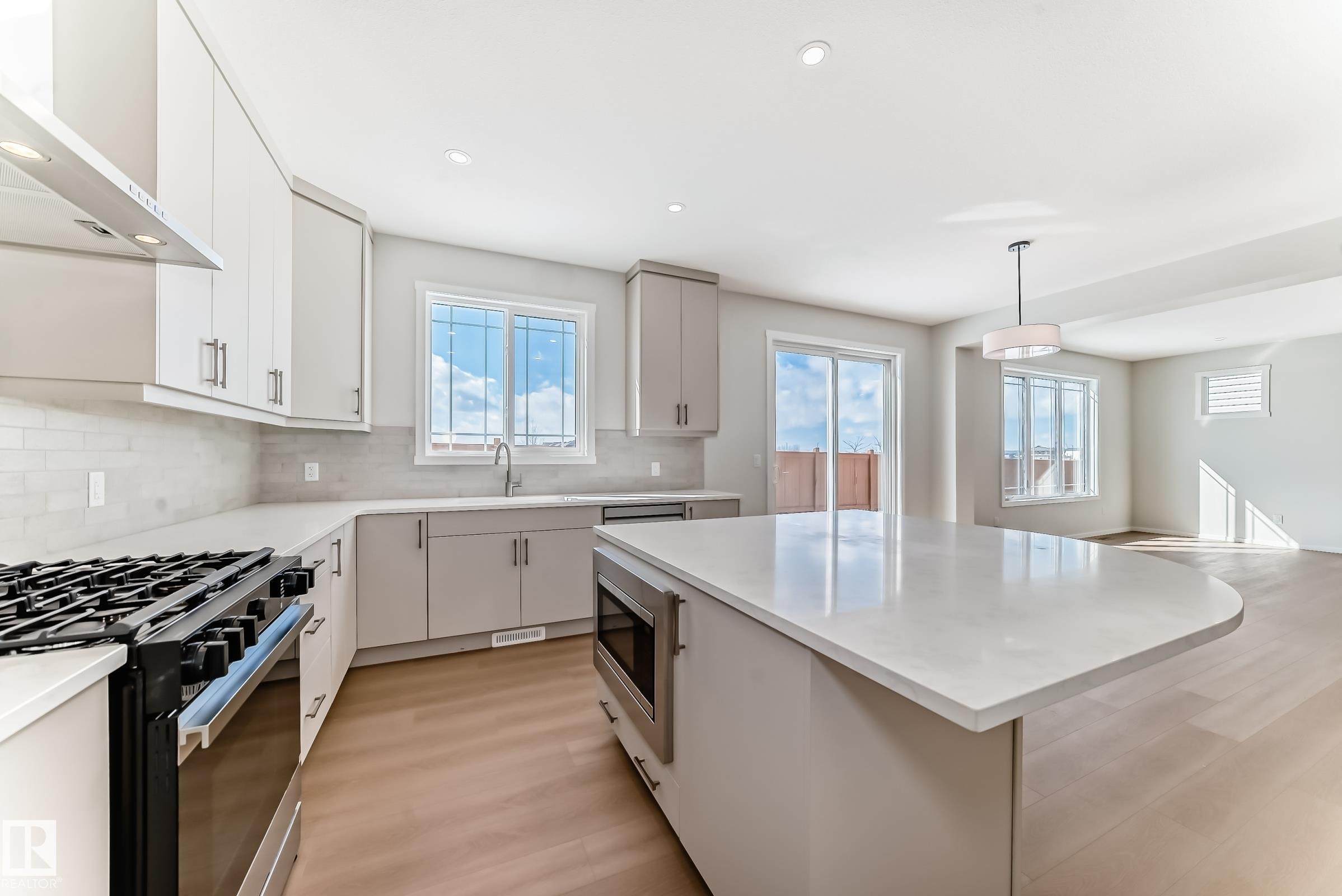 Open-concept kitchen with light-colored cabinetry, a modern range, and a spacious island featuring a microwave - 1516 206 Street Nw, Edmonton, AB - Indoor Photo Showing Kitchen With Upgraded Kitchen