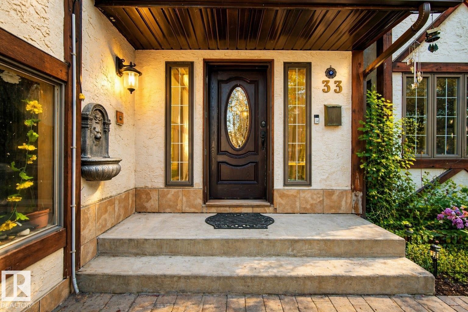 Inviting entrance featuring a dark wood-finish door with an oval glass insert, flanked by vertical sidelight windows - 33 Glen Meadow Crescent, St. Albert, AB - Outdoor With Deck Patio Veranda With Exterior