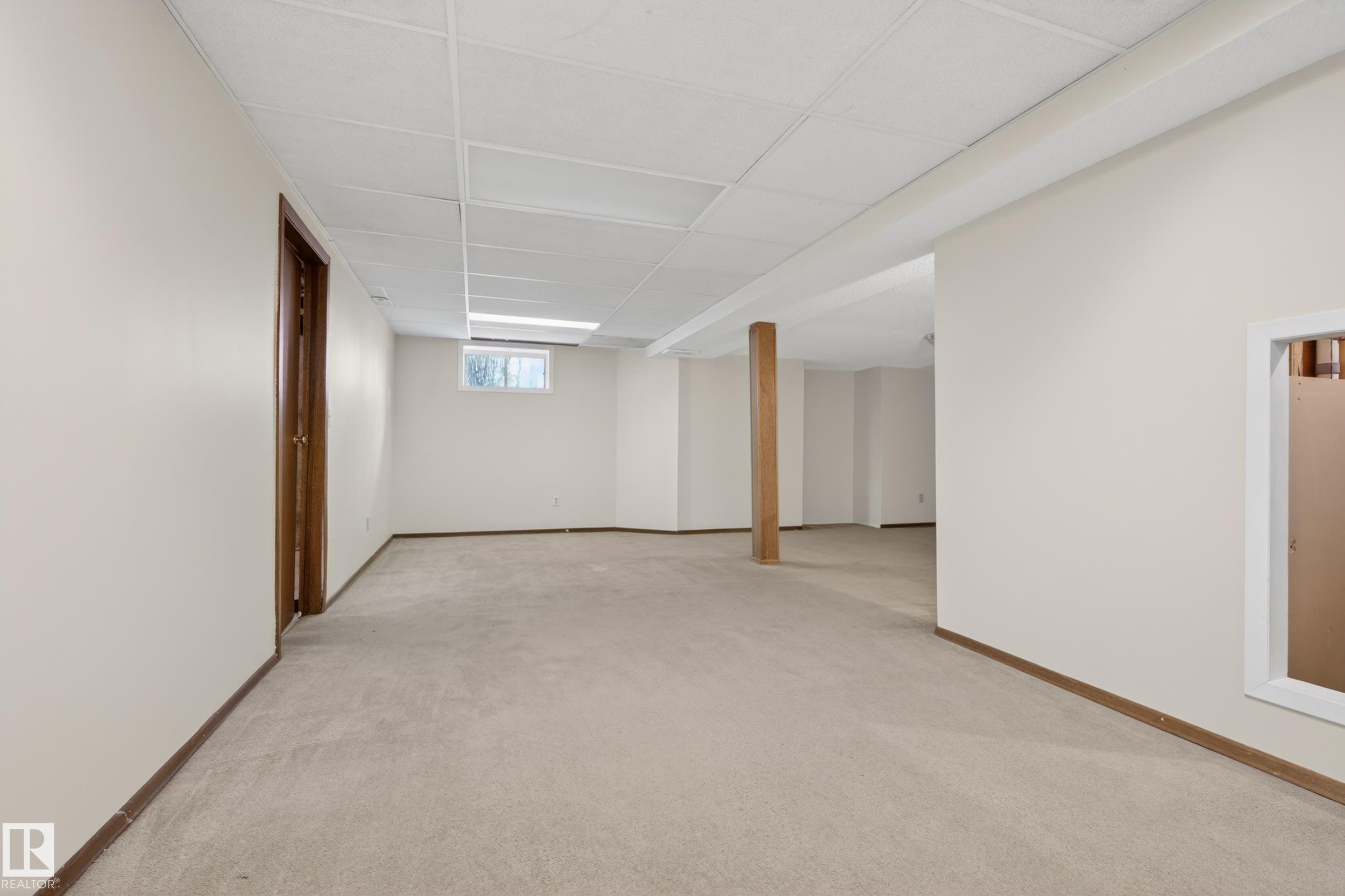 Expansive finished lower level featuring neutral carpet, light-toned walls, a drop ceiling, a small window, and a wood support column - 33 Glen Meadow Crescent, St. Albert, AB - Indoor