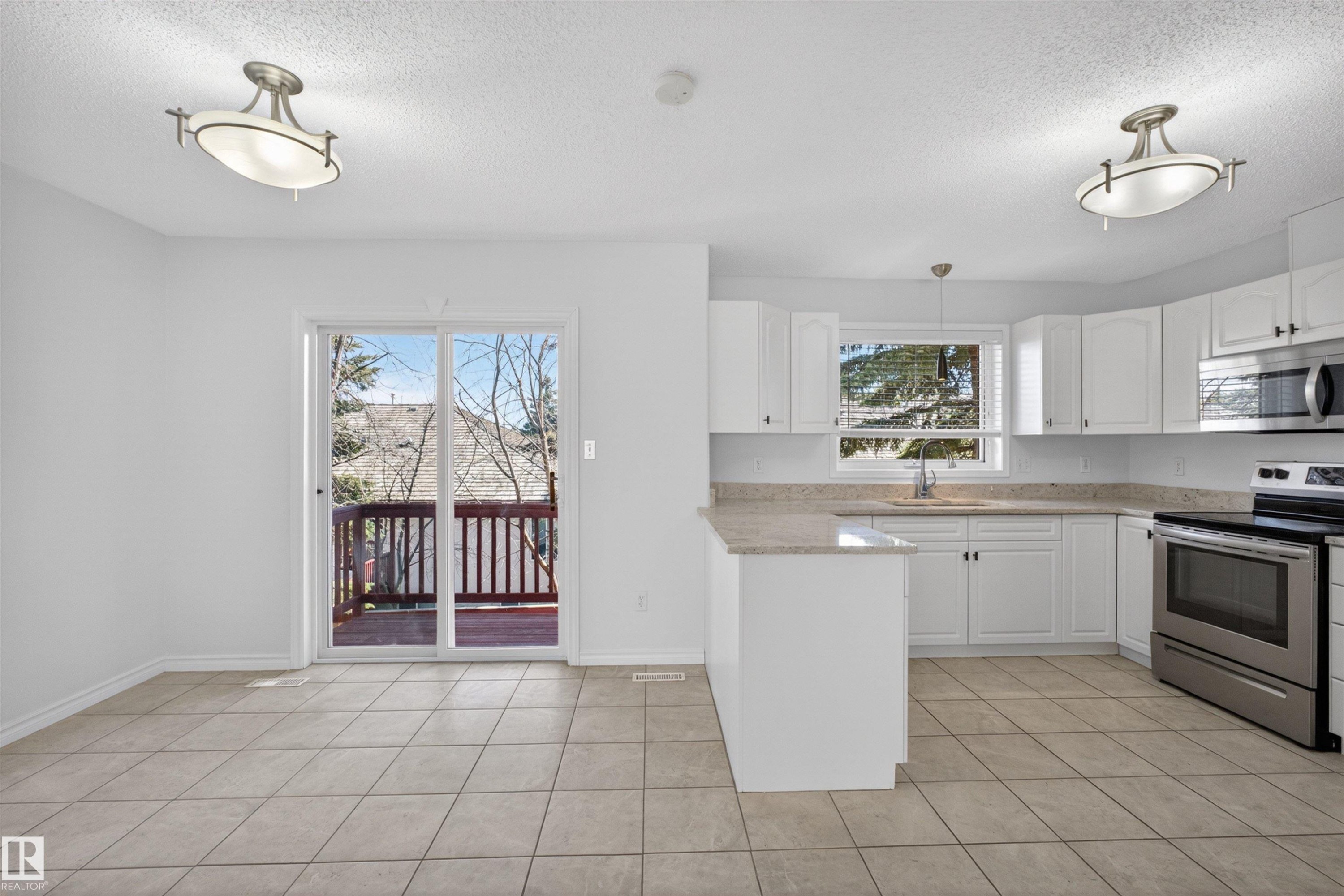 Kitchen space featuring tile flooring, white cabinetry, light-toned countertops, and stainless steel appliances - 6 1237 Carter Crest Road, Edmonton, AB