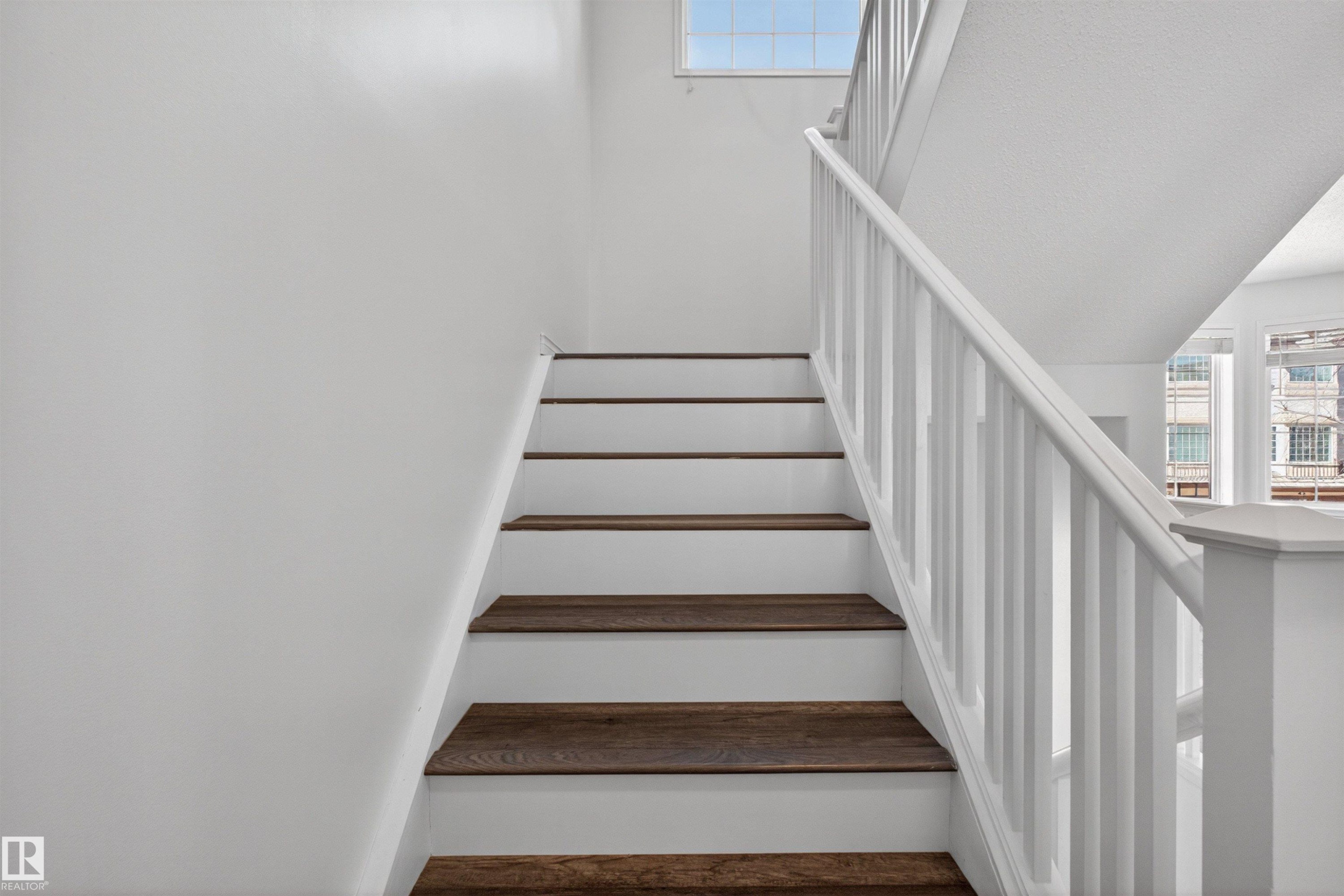 Staircase featuring wood-finish treads, white risers, and a white balustrade - 6 1237 Carter Crest Road, Edmonton, AB