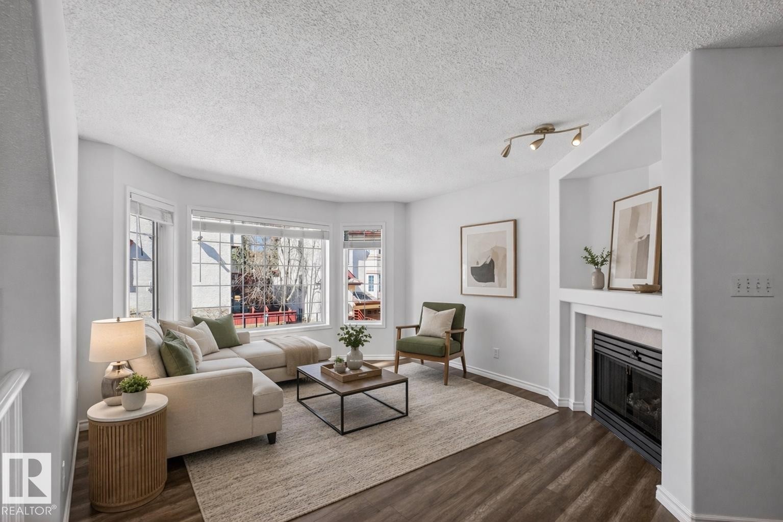 Living area featuring wood-finish flooring, a bay window with multiple panes, and a fireplace with a mantel - 6 1237 Carter Crest Road, Edmonton, AB