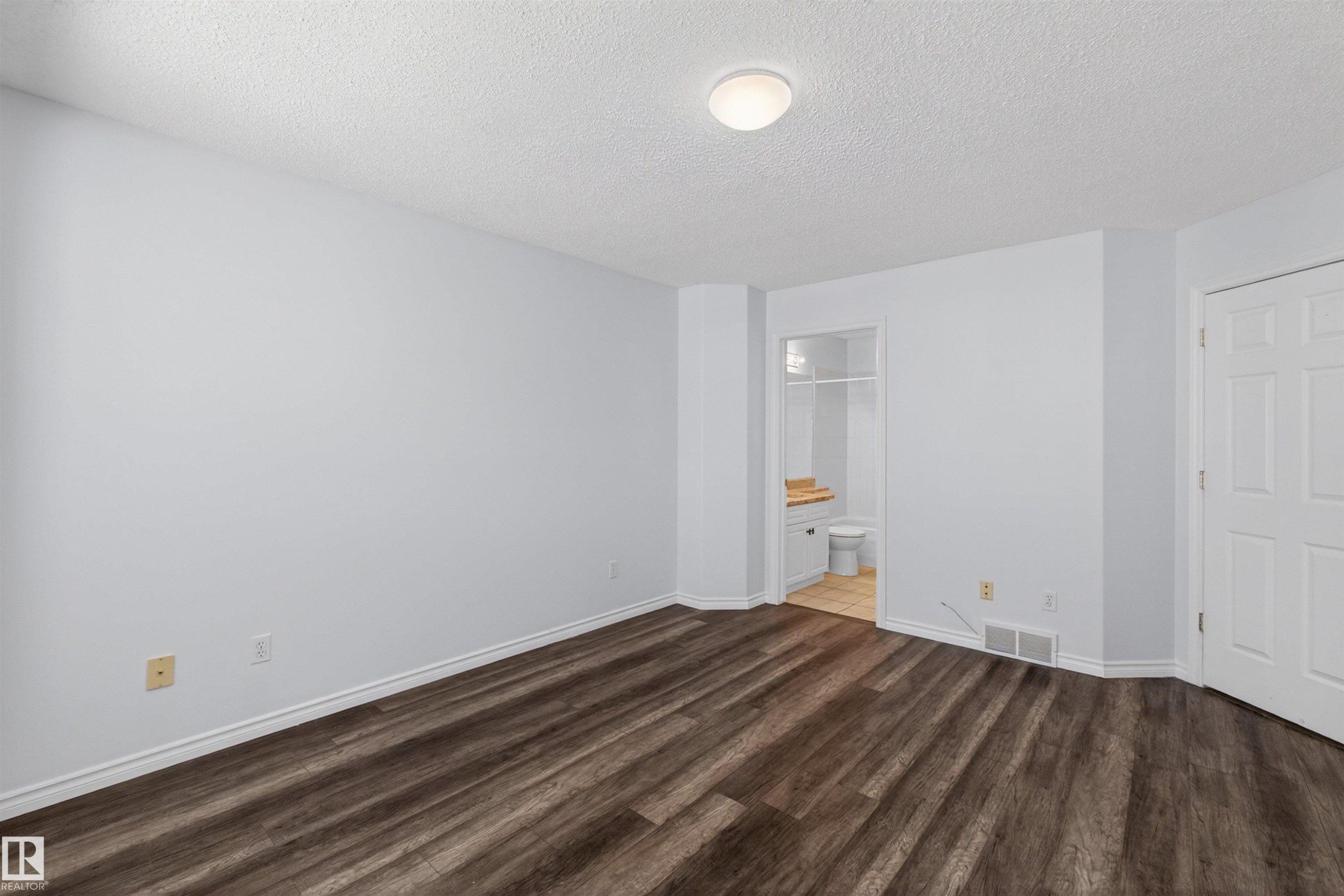 Spacious room featuring wood-finish flooring, light gray walls, and white baseboards - 6 1237 Carter Crest Road, Edmonton, AB