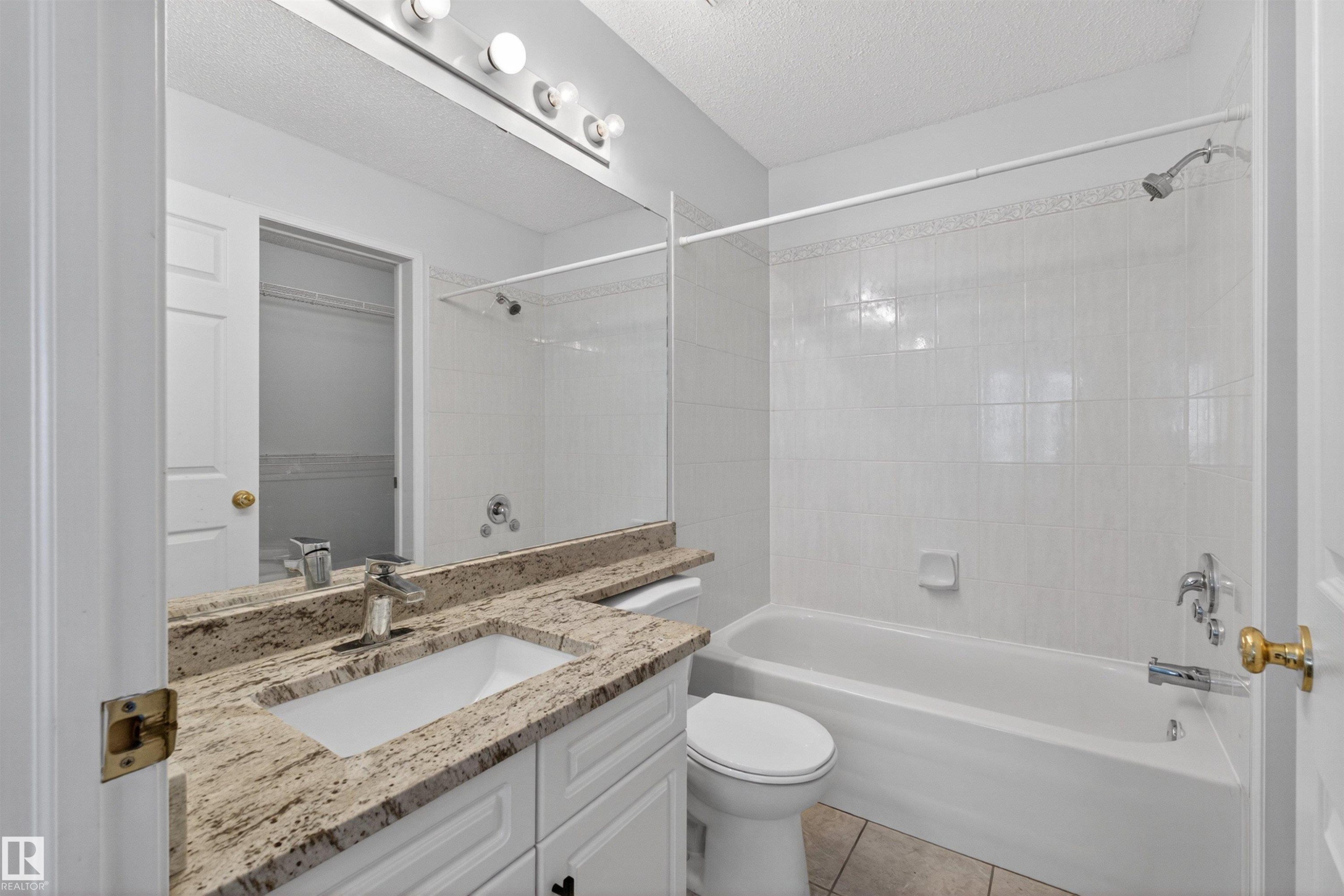 Bathroom featuring a vanity with a light-toned countertop, integrated sink, and white cabinetry - 6 1237 Carter Crest Road, Edmonton, AB