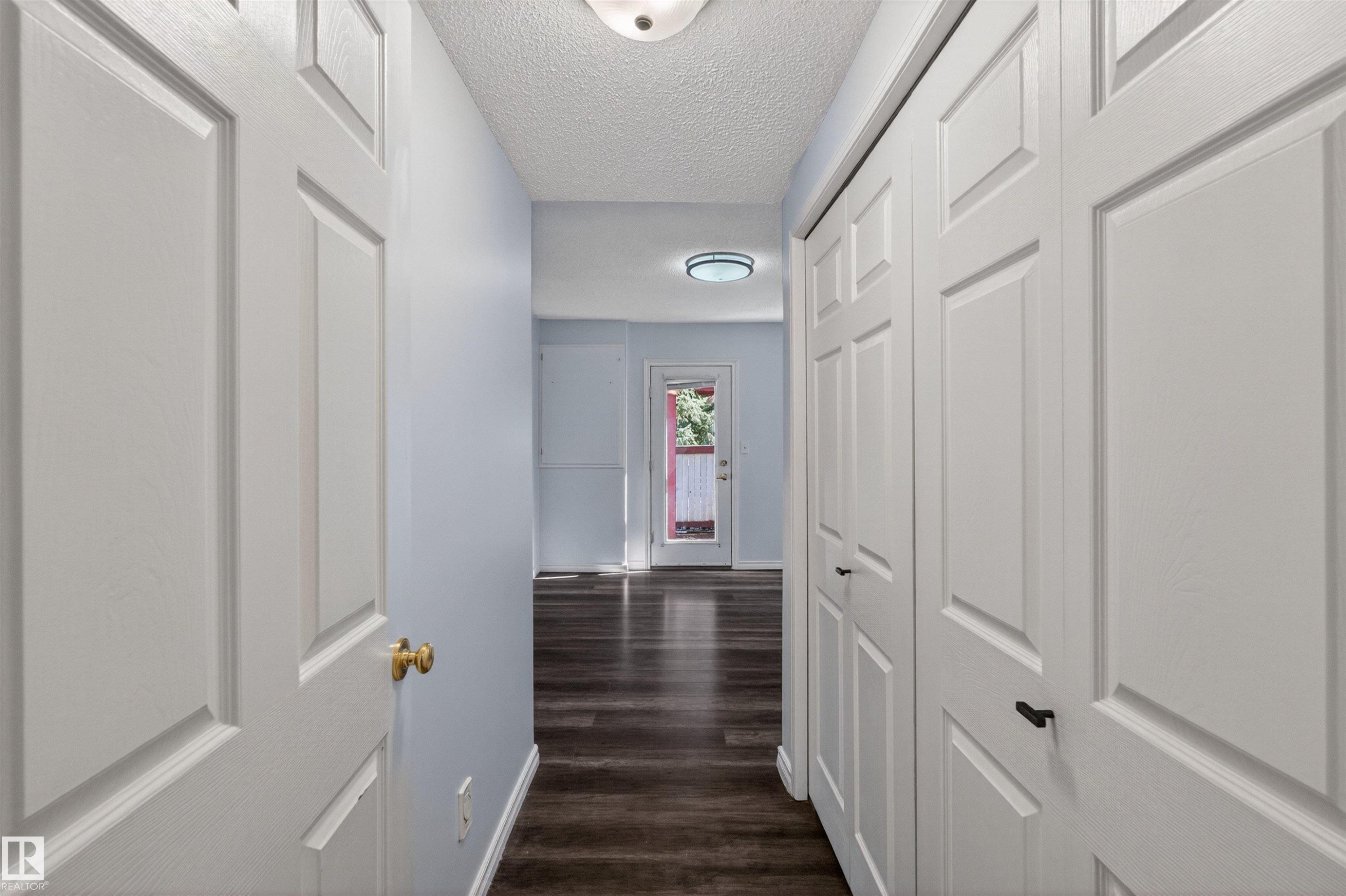 Hallway featuring wood-finish flooring, light blue wall paint, and white paneled doors - 6 1237 Carter Crest Road, Edmonton, AB