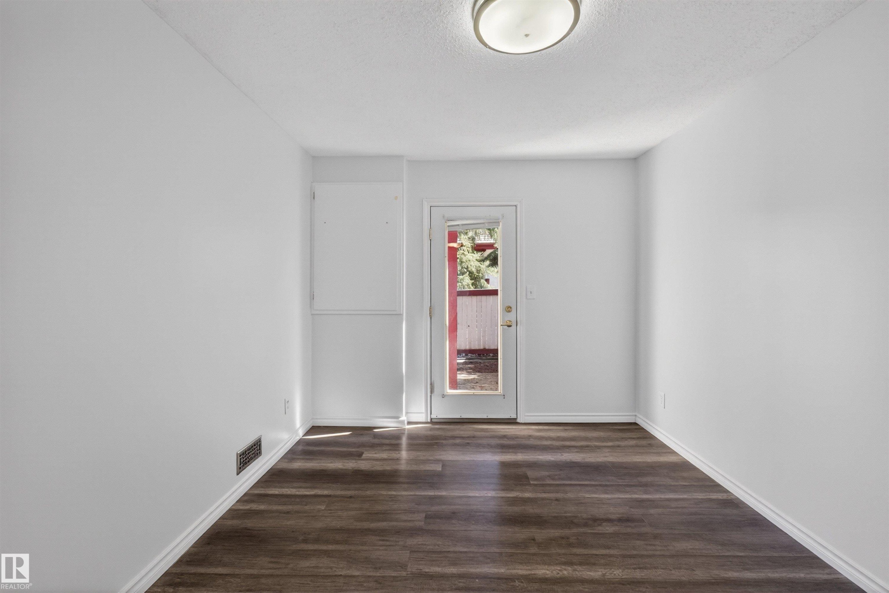 Interior space featuring wood-finish flooring, white baseboards, and a flush-mount ceiling light fixture - 6 1237 Carter Crest Road, Edmonton, AB
