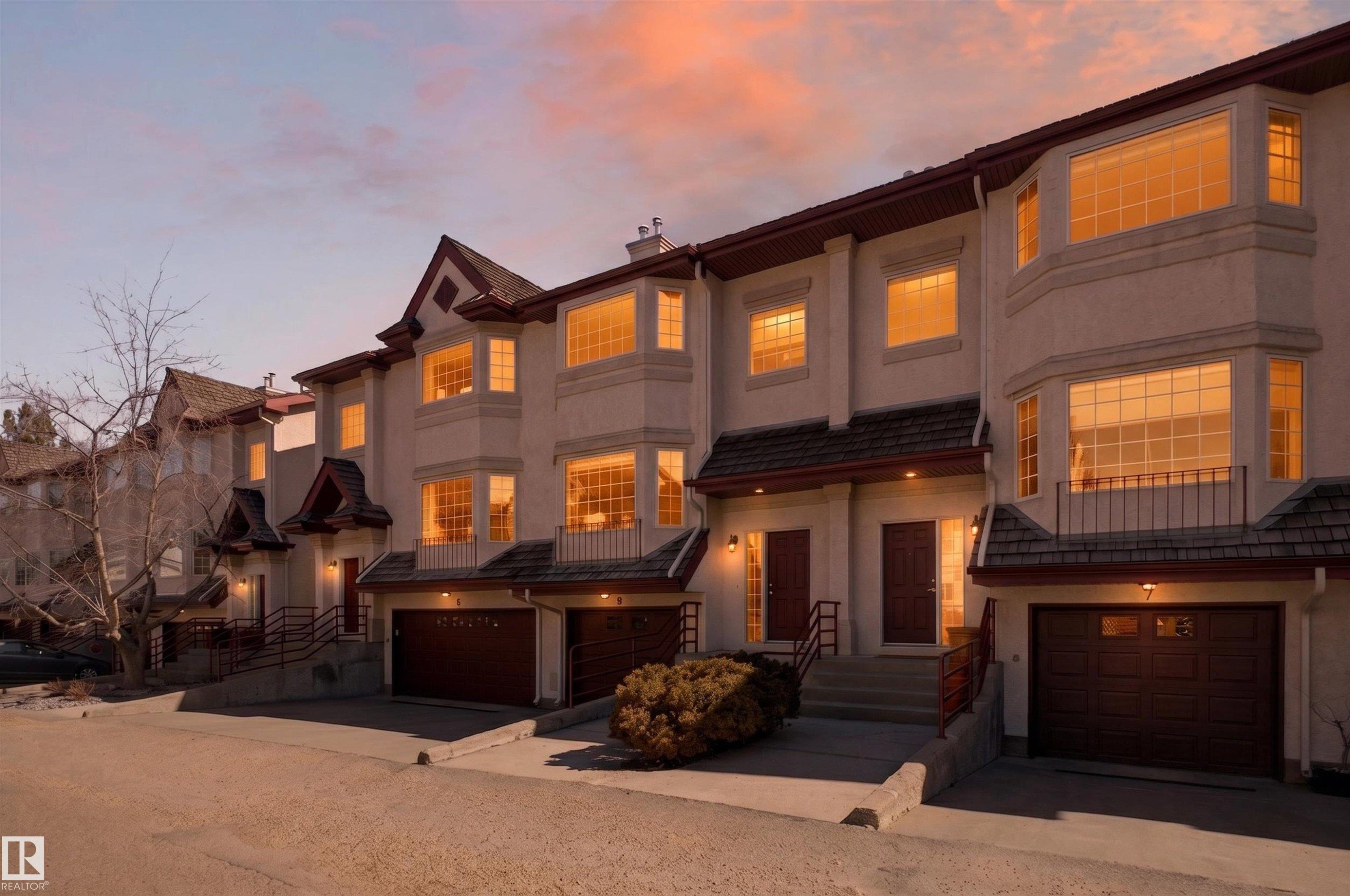 Multi-level townhome featuring a stucco exterior with dark trim and bay windows - 6 1237 Carter Crest Road, Edmonton, AB